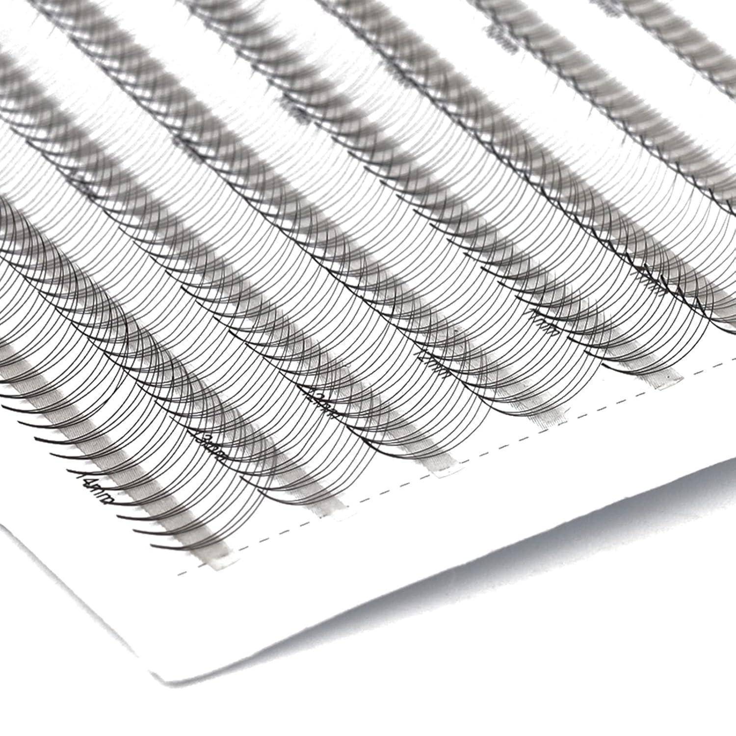 Nahaufnahme eines Tabletts mit künstlichen Wimpernverlängerungen, die in Reihen auf weißem Untergrund angeordnet sind.
