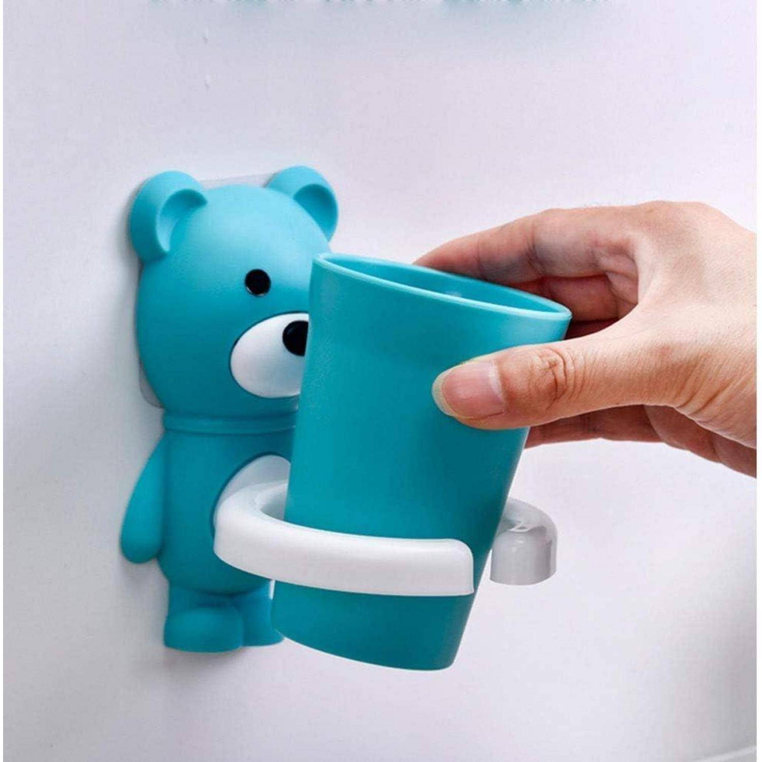 Hand setzt eine blaugrüne Tasse in einen bärenförmigen Wandhalter mit weißem Griff ein, wie ein dekorativer Tassen-Spender für Badezimmer oder Küche.