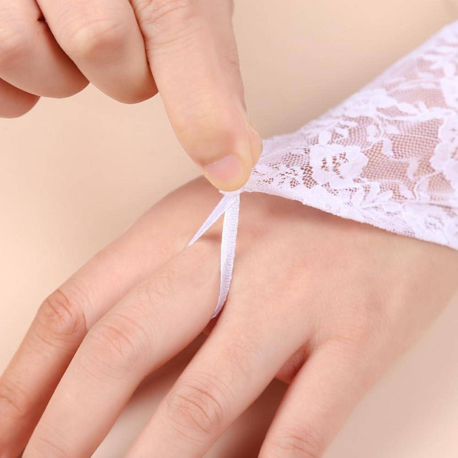 Nahaufnahme einer Hand, die ein weißes Spitzenkleidungsstück mit einer kleinen Schleifenbindung befestigt.