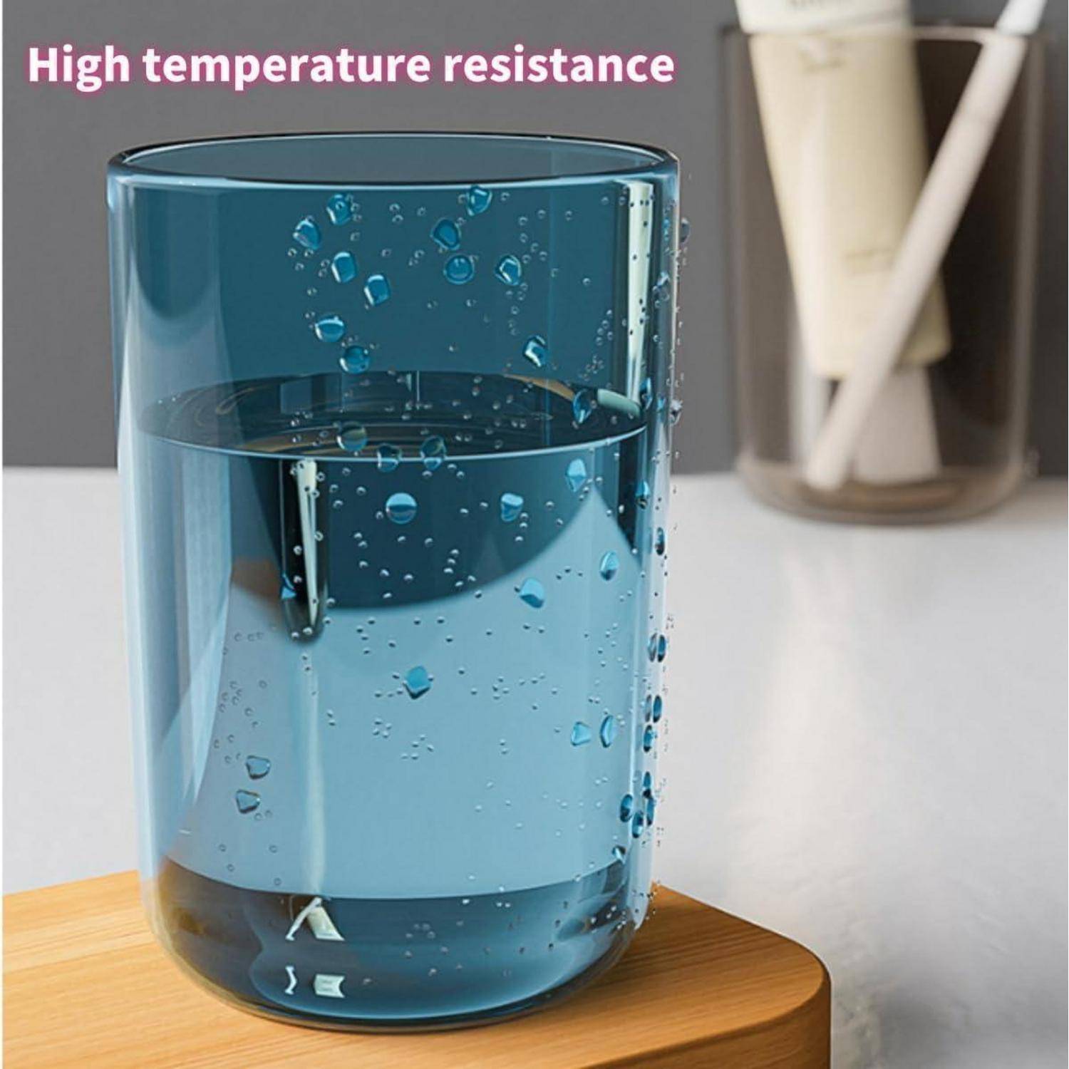 Blaues isoliertes Trinkglas auf einem Holzuntersetzer mit Wasser innen und Tropfen außen; Text sagt „Hitzebeständigkeit