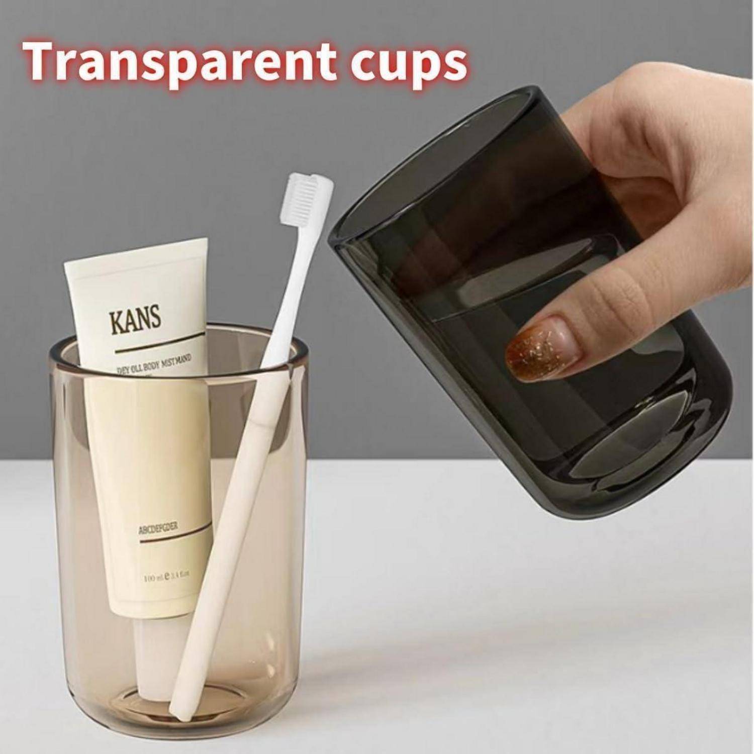 Produktbild zeigt zwei transparente Becher, einer hält eine Röhre und eine Zahnbürste, und eine Hand hält einen dunkel gerauchten Glasbecher; Text liest „Transparente Becher