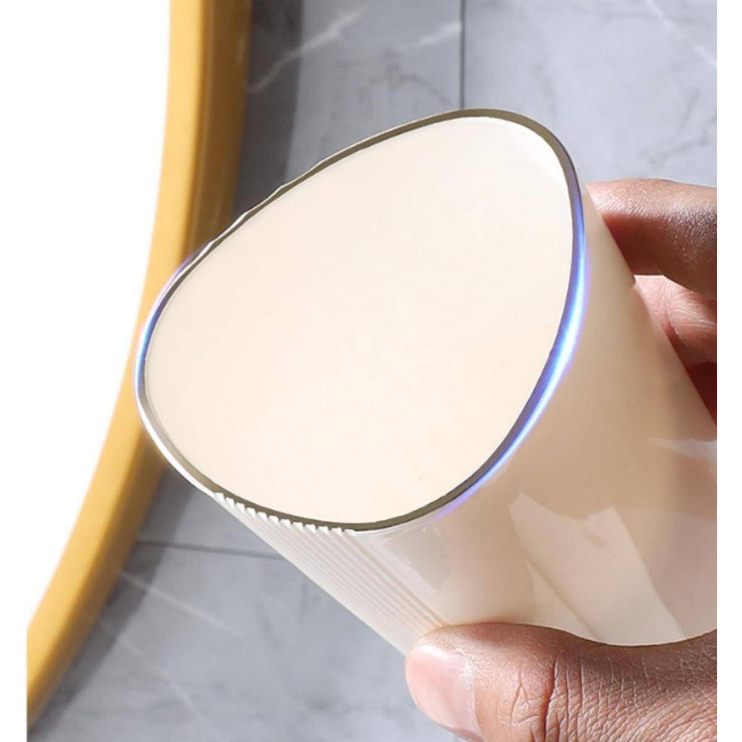 Nahaufnahme einer Hand, die einen weißen, sich verjüngenden Becher oder Trinkbecher mit glatter Kante und glänzender Oberfläche hält.