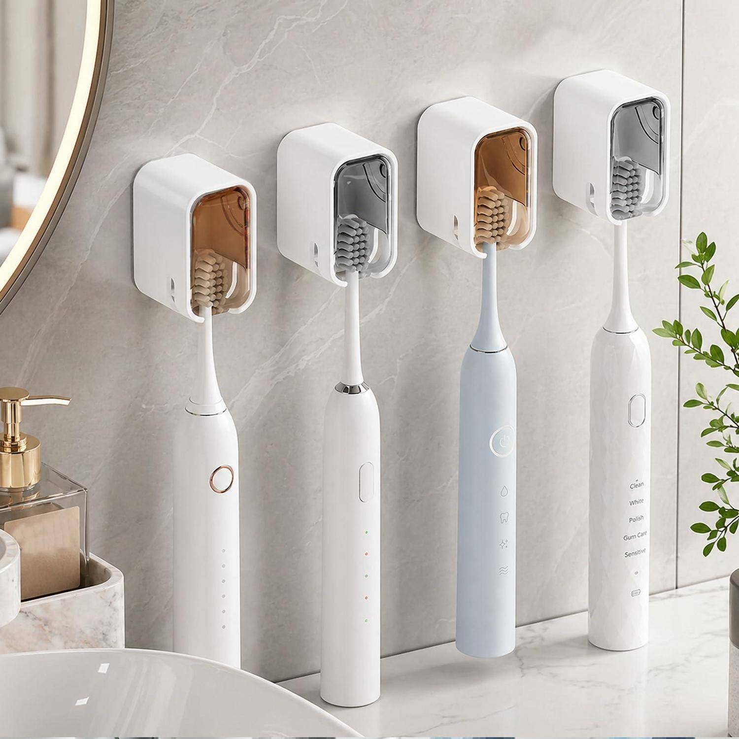 Vier elektrische Zahnbürsten in wandmontierten Ladestationen auf einem Badezimmertresen, mit einem Waschbecken und einer Pflanze daneben.