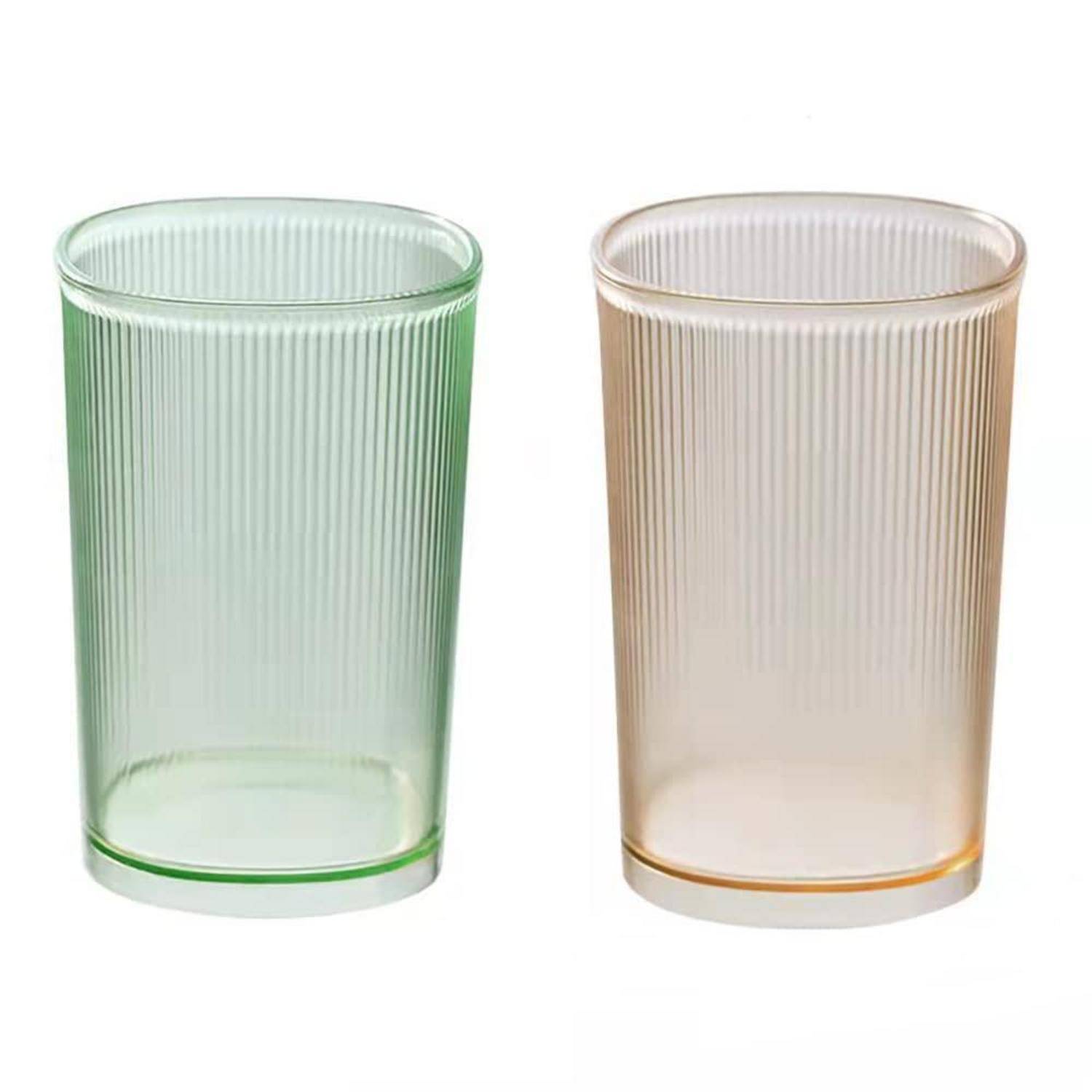 Zwei gerippte zylindrische Trinkgläser, eines grün und eines beige, nebeneinander auf weißem Hintergrund dargestellt.