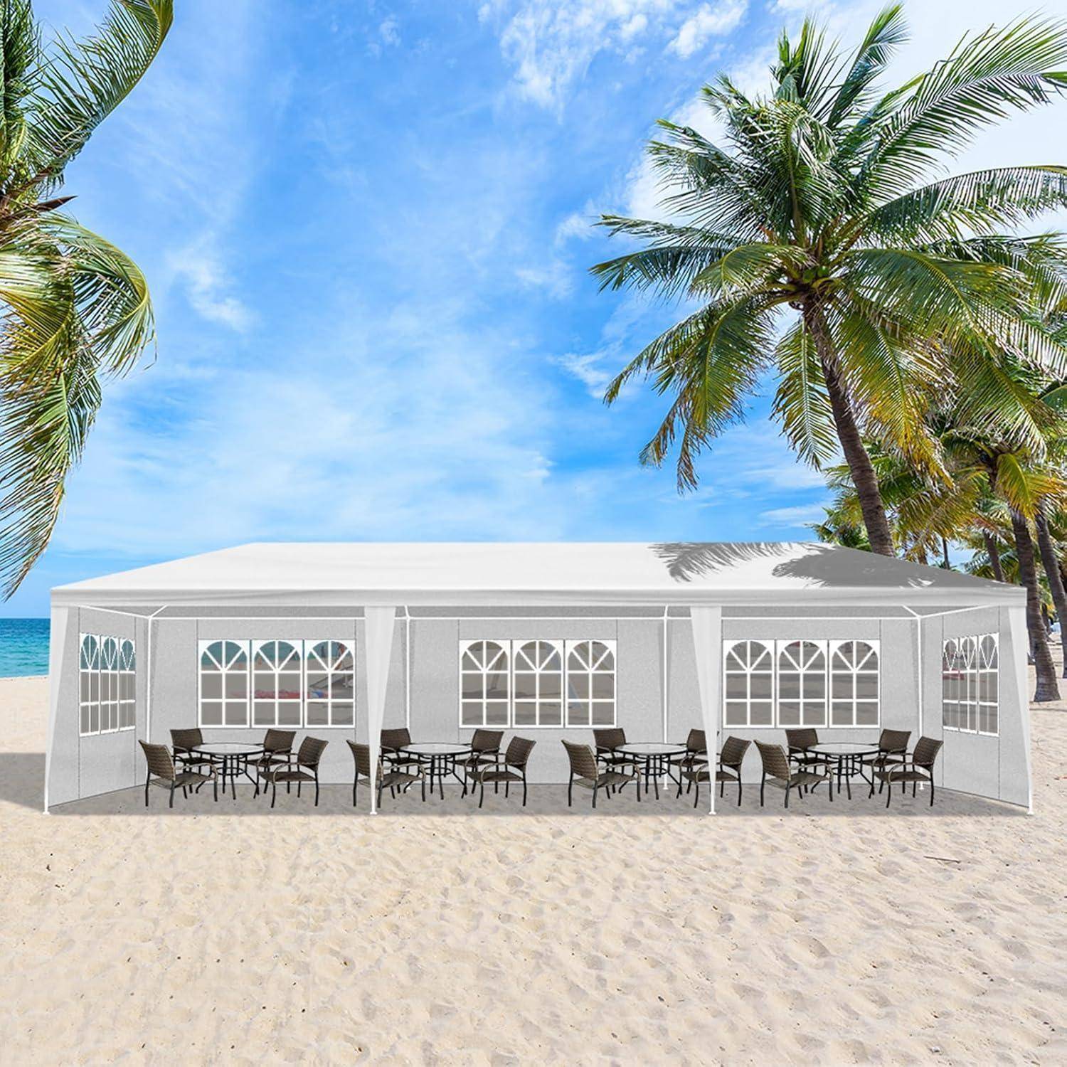 Weißes Strandveranstaltungszelt mit offenen Seiten, Tische und Stühle auf dem Sand, umrahmt von Palmen und Ozean unter blauem Himmel.