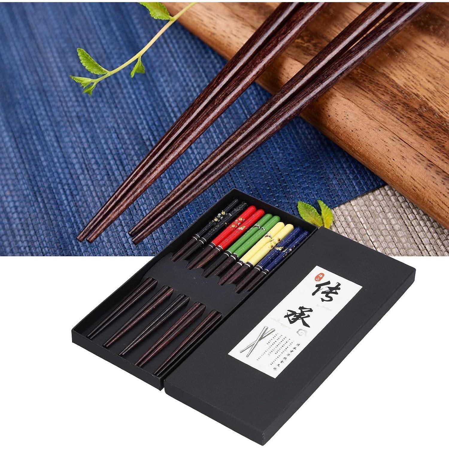 Schwarzes Essstäbchen-Geschenkset mit hölzernen Essstäbchen in einer Präsentationsbox und einem japanisch gestalteten Etikett, gezeigt auf einer blauen geflochtenen Matte mit einem Holztablett.