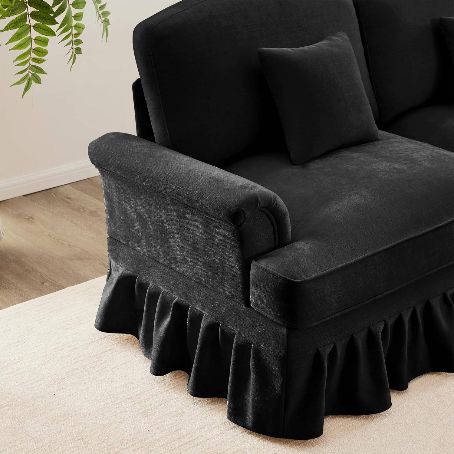 Schwarzes, gepolstertes Sofa mit angepasstem Schonbezug und gerafftem Saumabschluss in einem hellen Raum, in Großaufnahme am Arm und Sitz dargestellt.