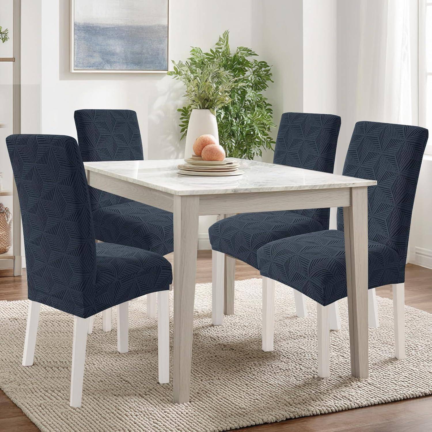Esszimmer-Set mit vier dunkelblau gepolsterten Stühlen um einen Tisch aus hellem Holz auf einem cremefarbenen Teppich in einem hellen Raum.