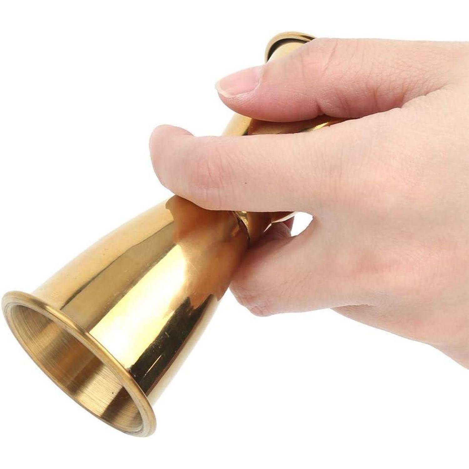 Eine Hand hält eine Messingglocke gegen einen weißen Hintergrund.