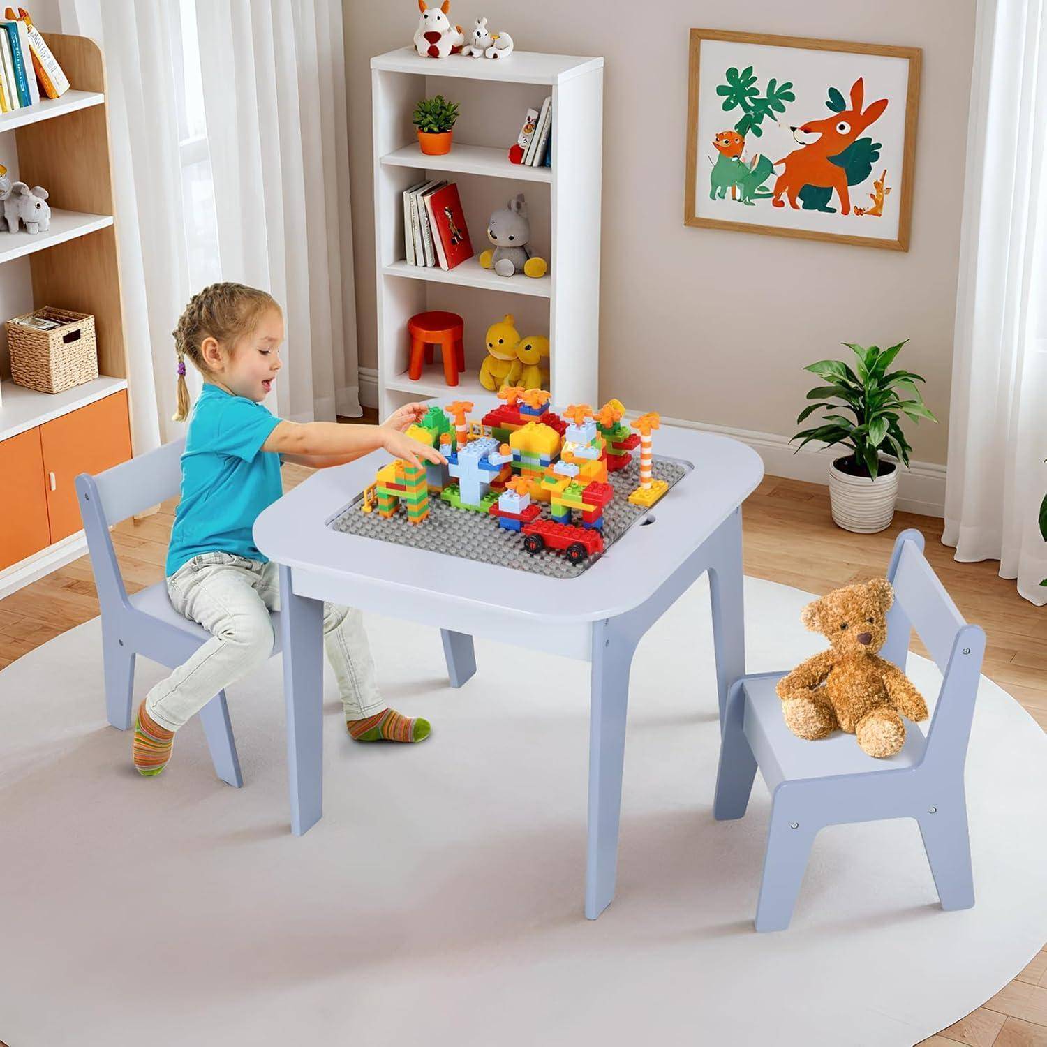 Junges Kind, das mit Bauklötzen an einem kleinen Tisch in einem hellen Spielzimmer spielt, mit Spielzeug, Regalen und einem Teddybär in der Nähe.