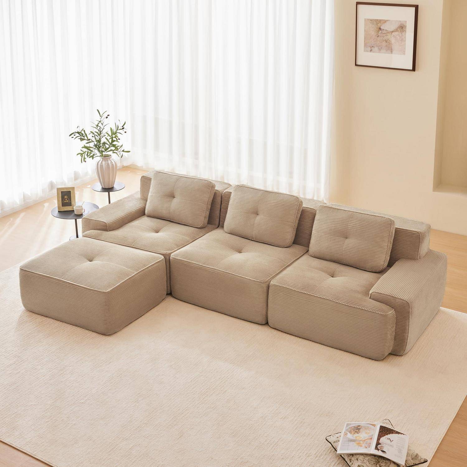 Beige modulares Sofa mit Ottomane in einem hellen, minimalistischen Wohnzimmer neben einem kleinen Beistelltisch und einer Pflanze.