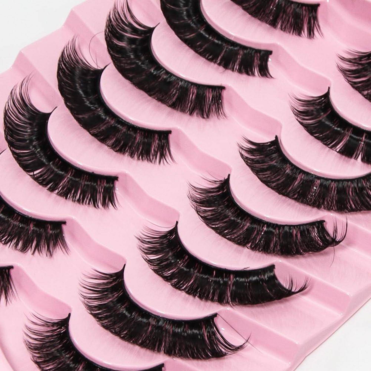 Mehrere Paar künstliche Wimpern, die in Reihen auf rosa Tabletts angeordnet sind.