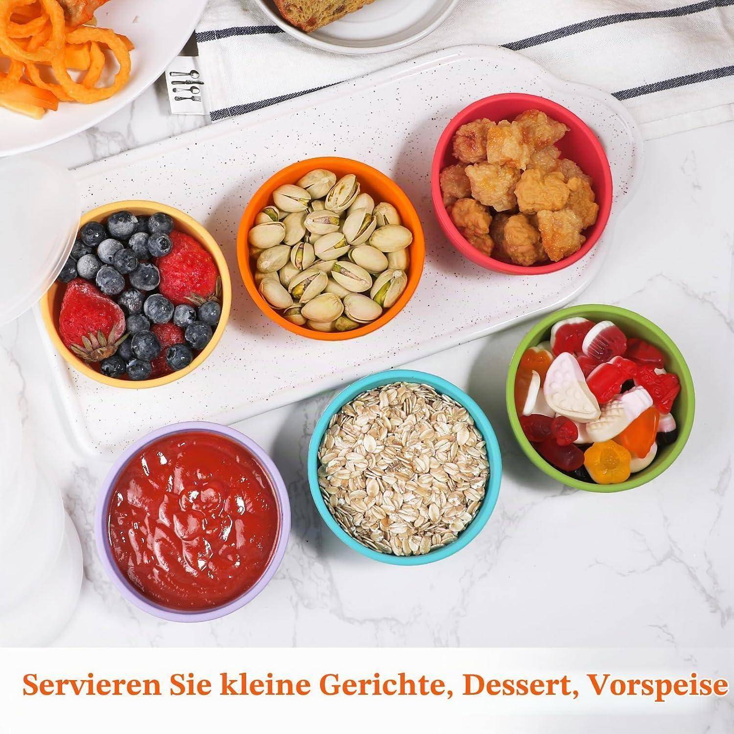 Farbenfrohe Schüsseln mit Nüssen, Beeren, Hafer, Sauce und Obst auf einem Tablett, mit deutschem Text darunter: 'Servieren Sie kleine Gerichte, Dessert, Vorspeise'.