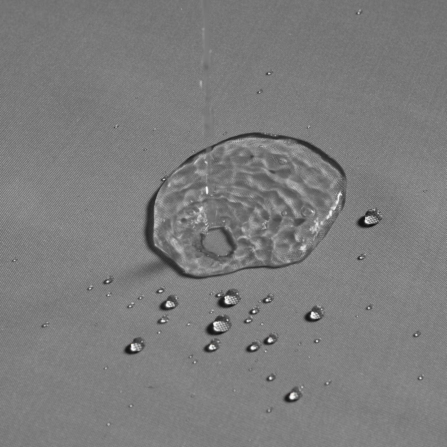 Nahaufnahme eines klaren Wassertropfens auf einer ebenen Oberfläche, umgeben von kleineren Tropfen.