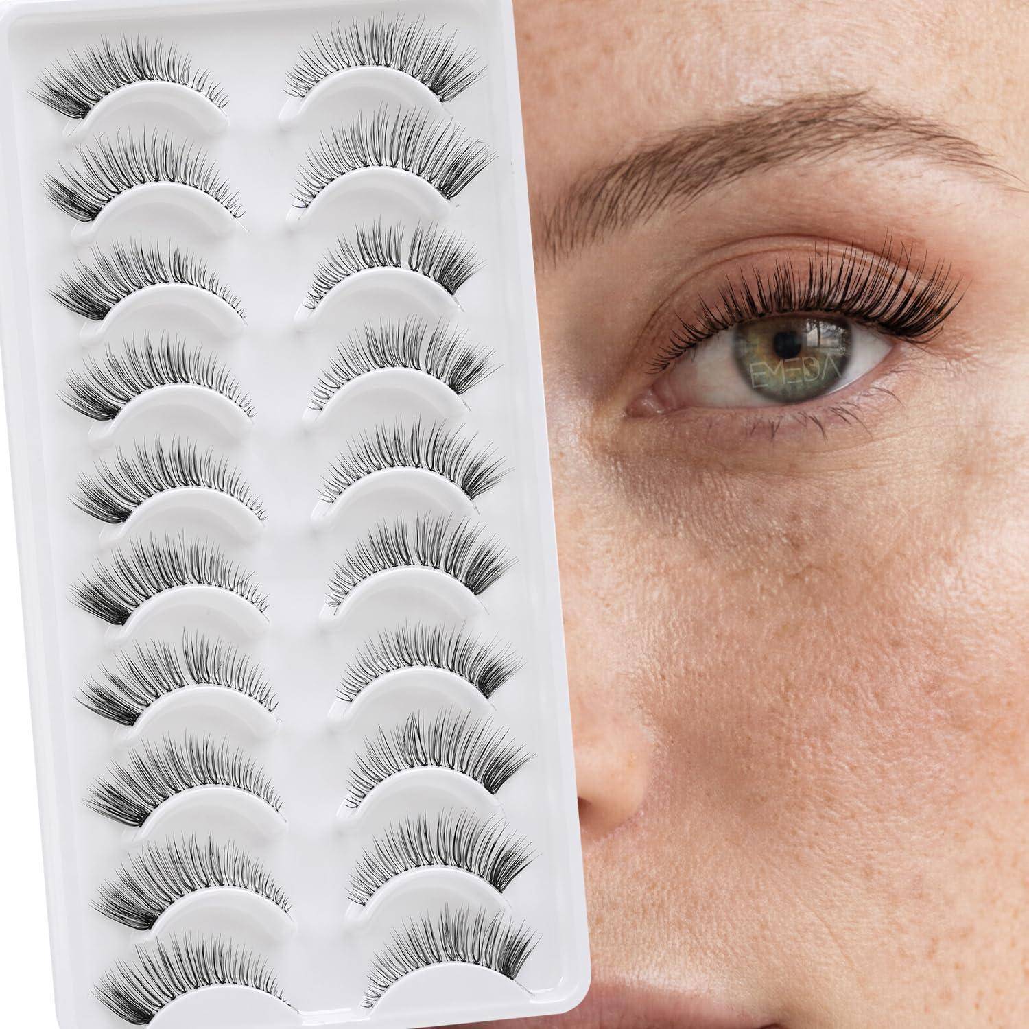 Nahaufnahme einer Frau, die lange künstliche Wimpern trägt, neben einem Tablett mit verschiedenen Paaren künstlicher Wimpern.