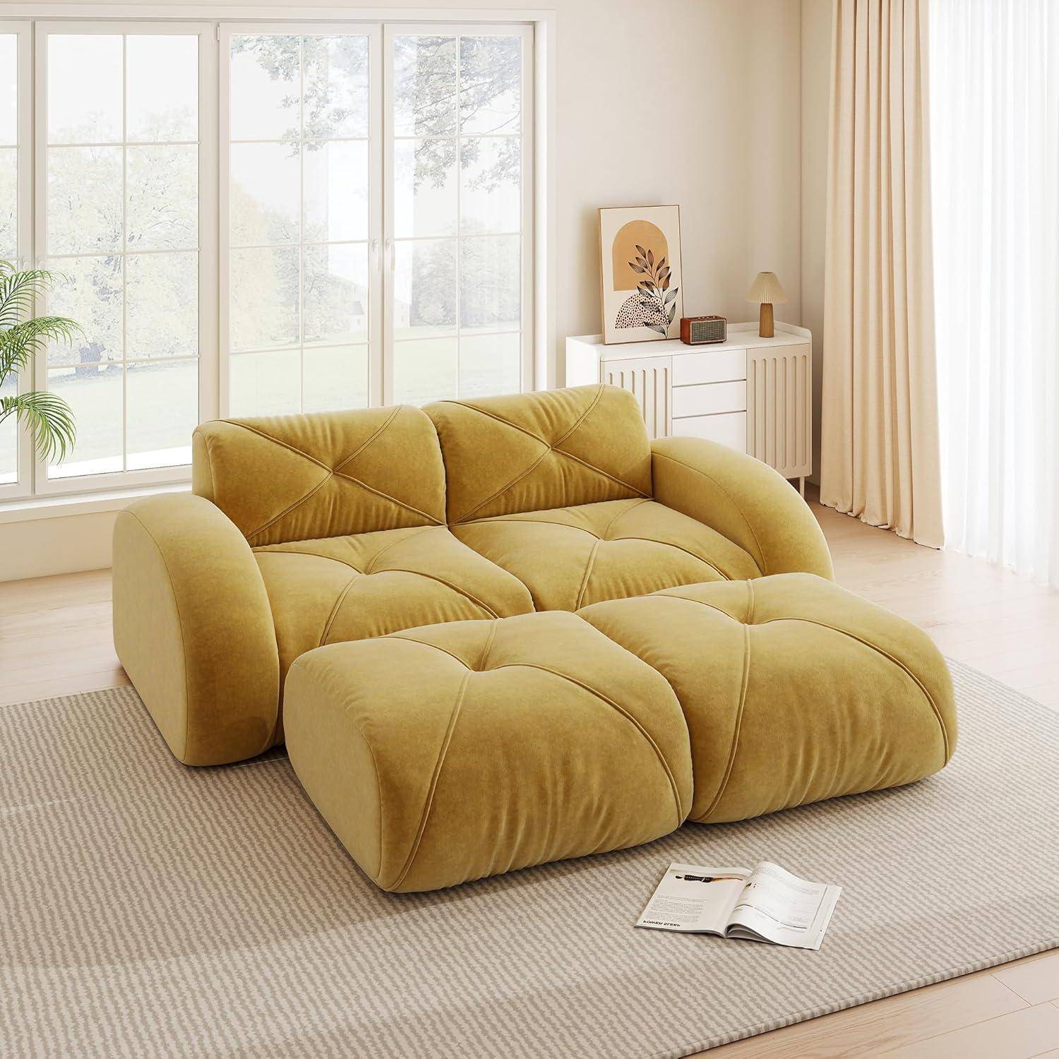 Senfsgelbes modulares Sofa mit übergroßem Sitzkissen in einem hellen minimalistischen Wohnzimmer neben einem Fenster, mit einem kleinen Sideboard, Gardinen und einem aufgeschlagenen Buch auf dem Teppich.