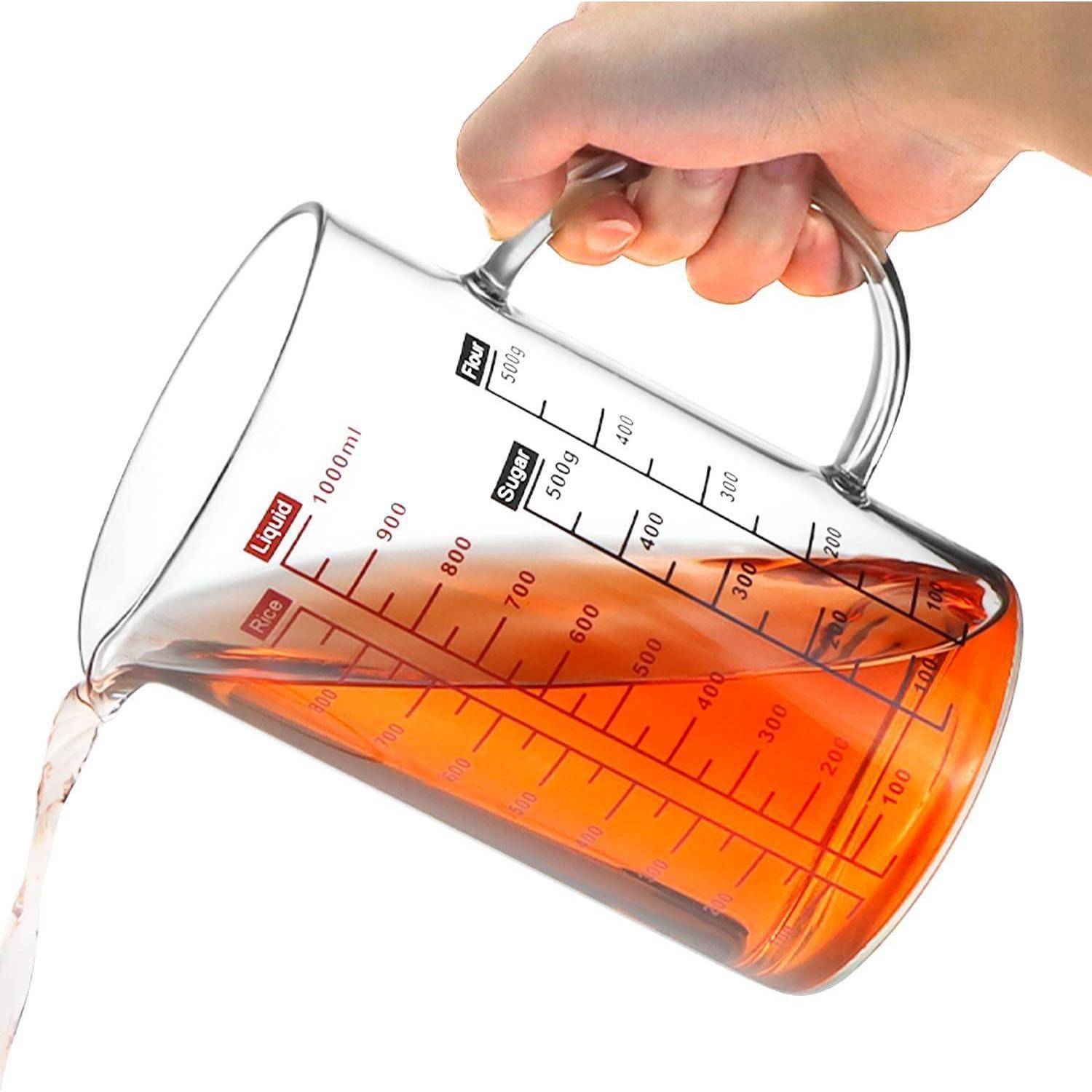 Hand, die einen Glaskrug zum Messen neigt, orangefarbige Flüssigkeit gießend; gekennzeichnet mit Volumen- und Zutatenskalen.