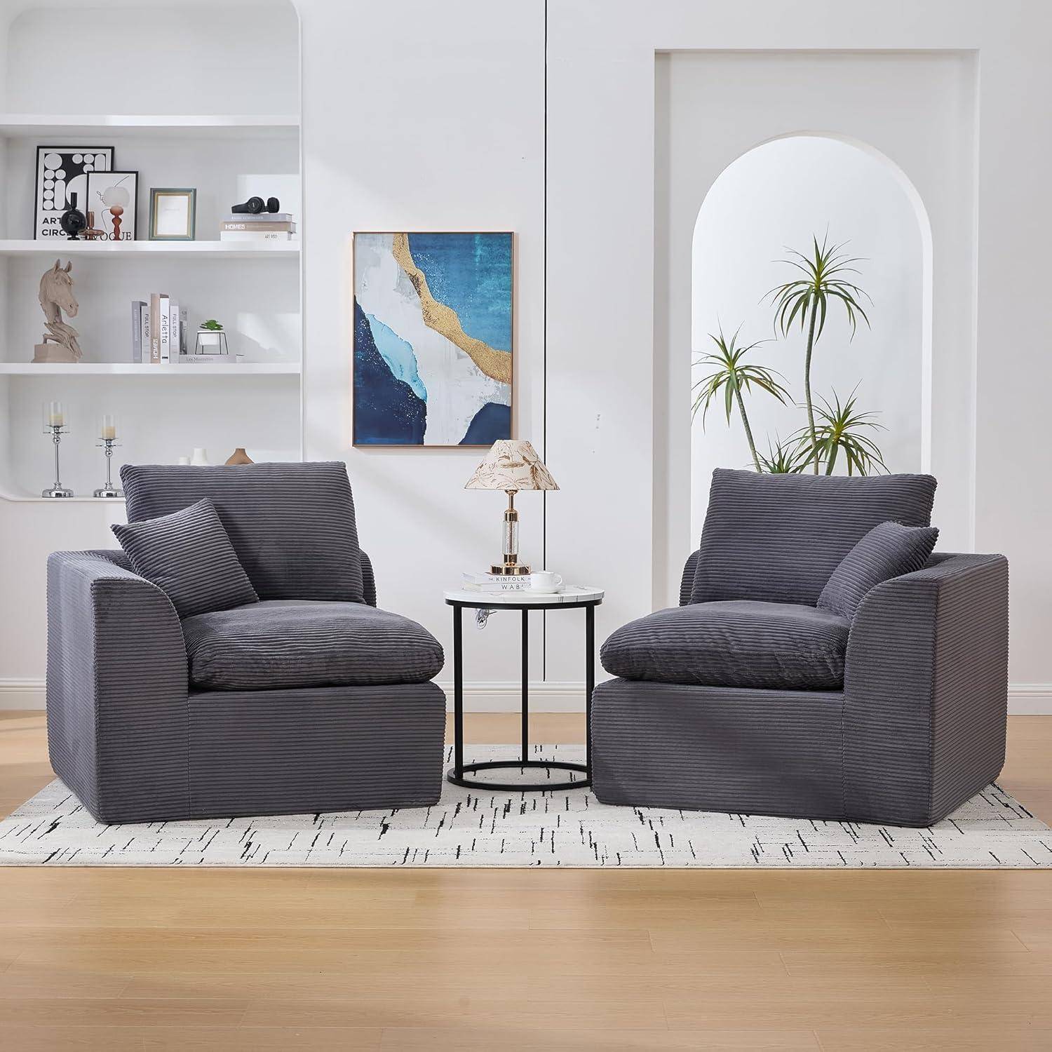 Zwei graue Sessel stehen sich in einem hellen, modernen Wohnzimmer gegenüber, mit einem kleinen Beistelltisch und einer Lampe dazwischen.