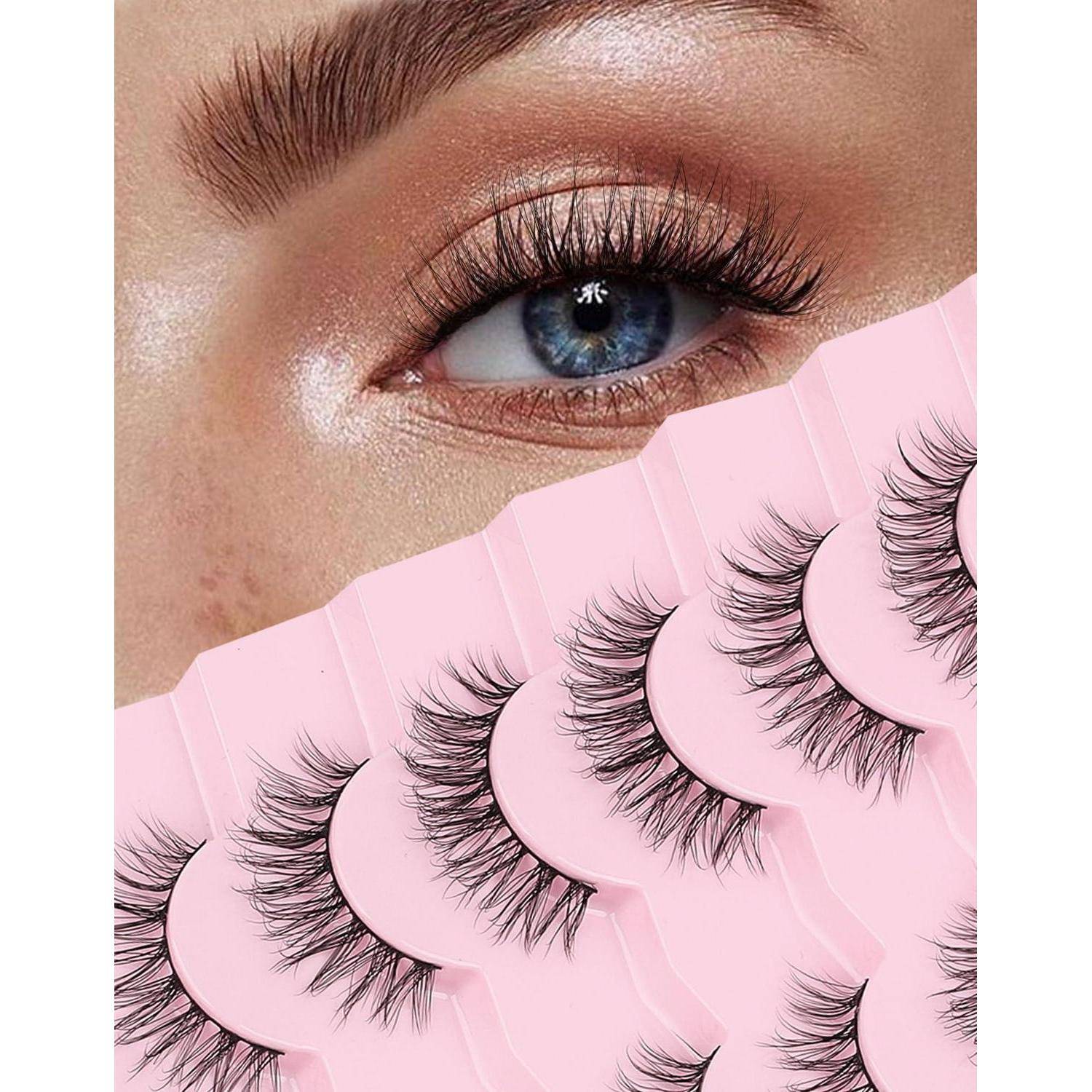 Nahaufnahme eines blauen Auges mit langen Wimpern über mehreren Streifen von künstlichen Wimpern auf rosa Verpackung.
