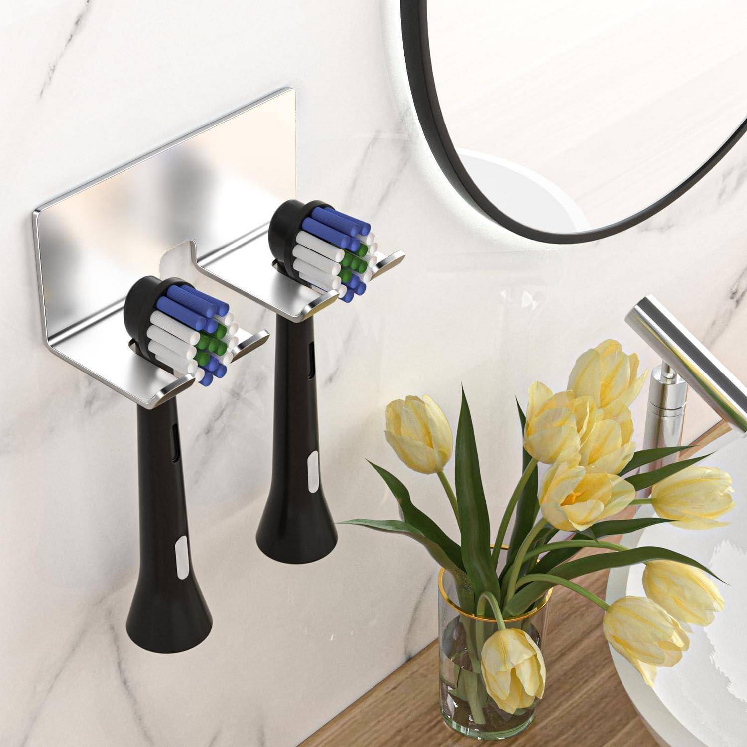 Wandmontierte Zahnbürstenhalter im Badezimmer neben einem Spiegel, mit gelben Tulpen in einer Glasvase auf einer Holzarbeitsplatte.