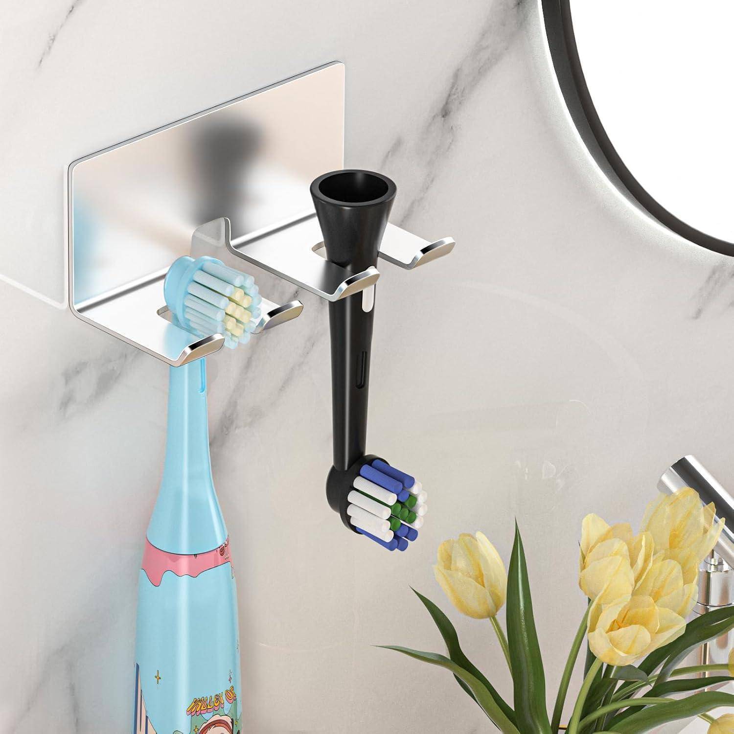 An der Wand angebrachter Zahnbürstenhalter mit zwei elektrischen Zahnbürsten und einer Zahnpastatube neben gelben Blumen an einer Badezimmerwand mit Marmormuster.