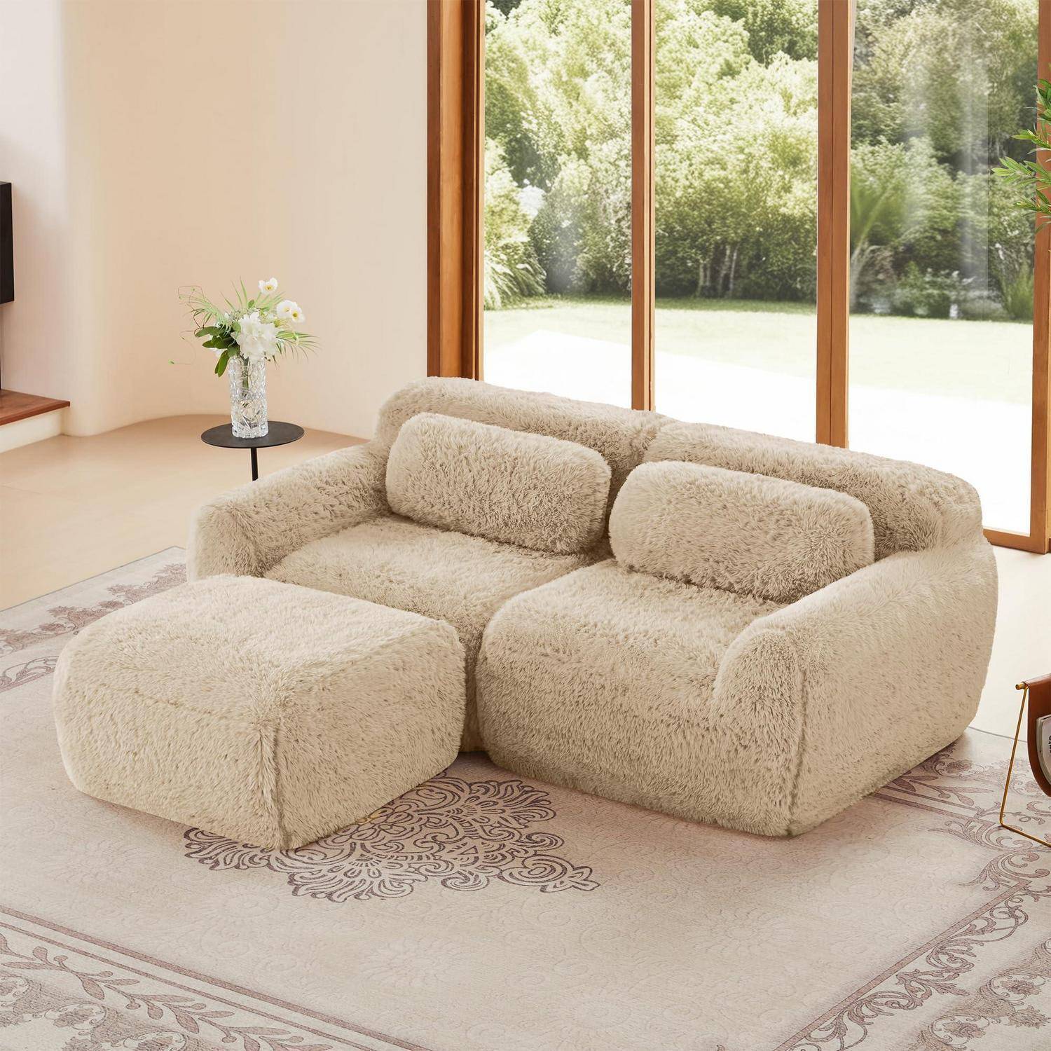 Beige flauschiges Ecksofa mit Ottomane in einem hellen Wohnzimmer neben großen Fenstern mit Blick auf Grünflächen.