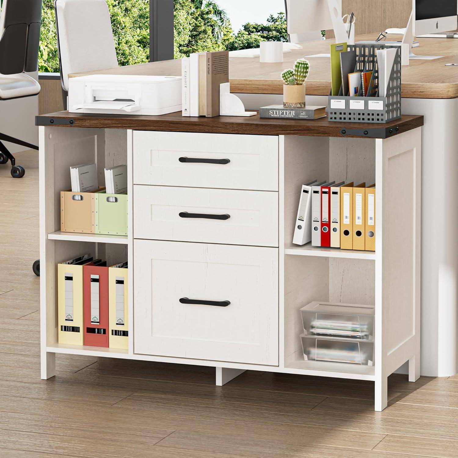 Weißer Bürolagerschrank mit drei Schubladen, offenen Regalen und Holzplatte, auf dem Aktenordner und Schreibtischartikel in einem hellen Arbeitsbereich gelagert werden.