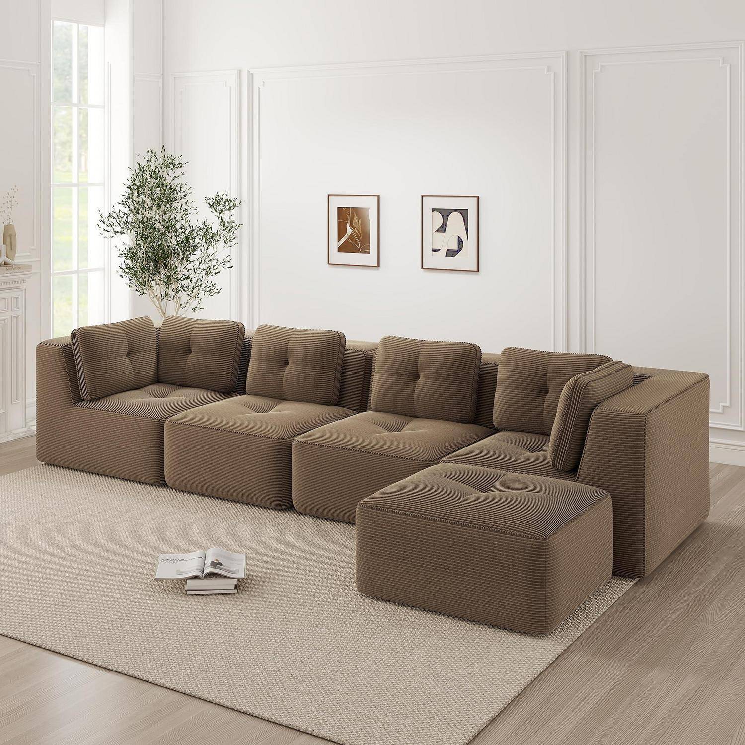 Modernes braunes modulares Ecksofa mit Chaiselongue in einem hellen minimalistischen Wohnzimmer, mit gerahmter Wandkunst, Pflanze, Teppich und aufgeschlagenem Buch auf dem Boden.