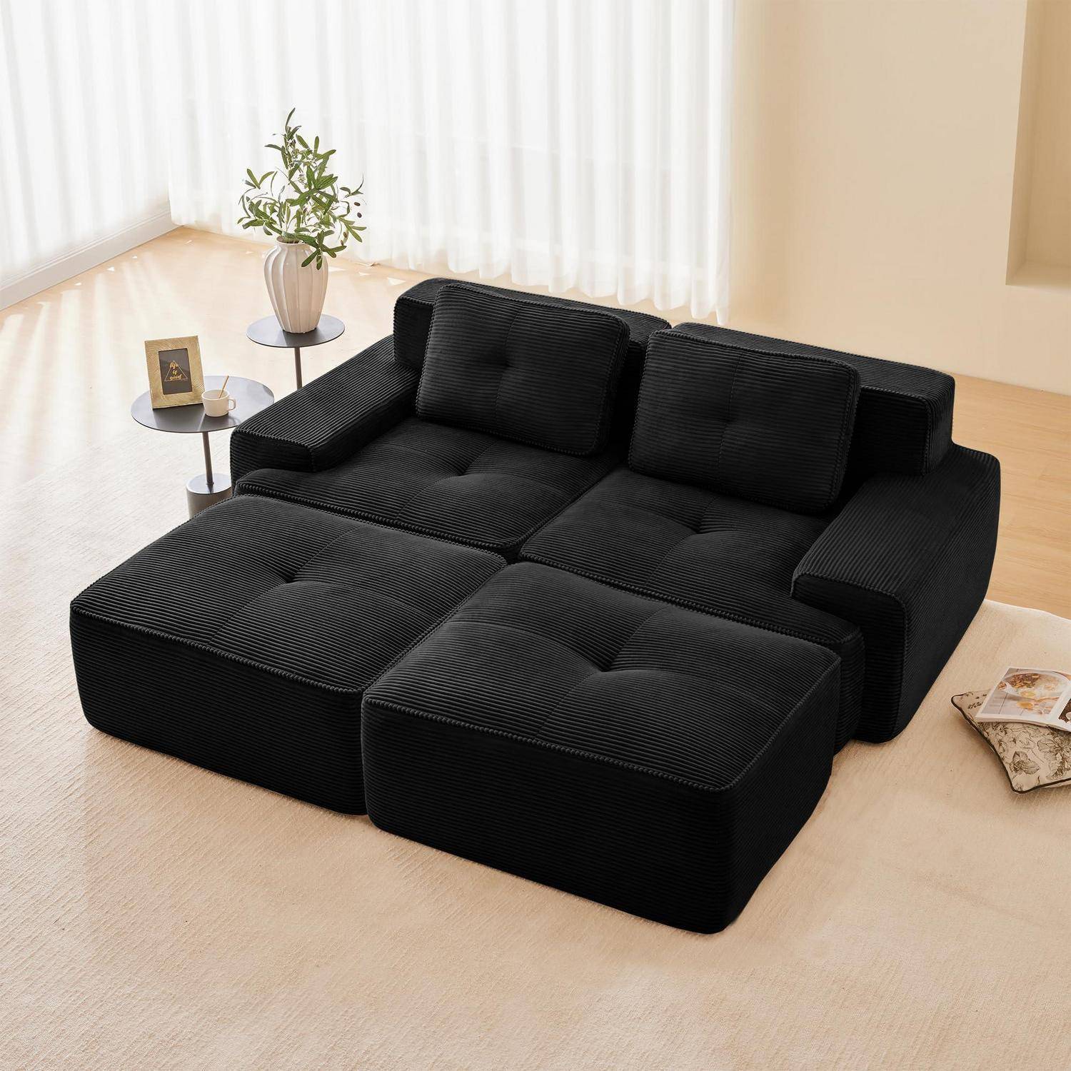 Schwarzes modulares Ecksofa mit zwei Rückenkissen, einem kleinen Beistelltisch und einer Pflanze in einem hellen minimalistischen Wohnzimmer.