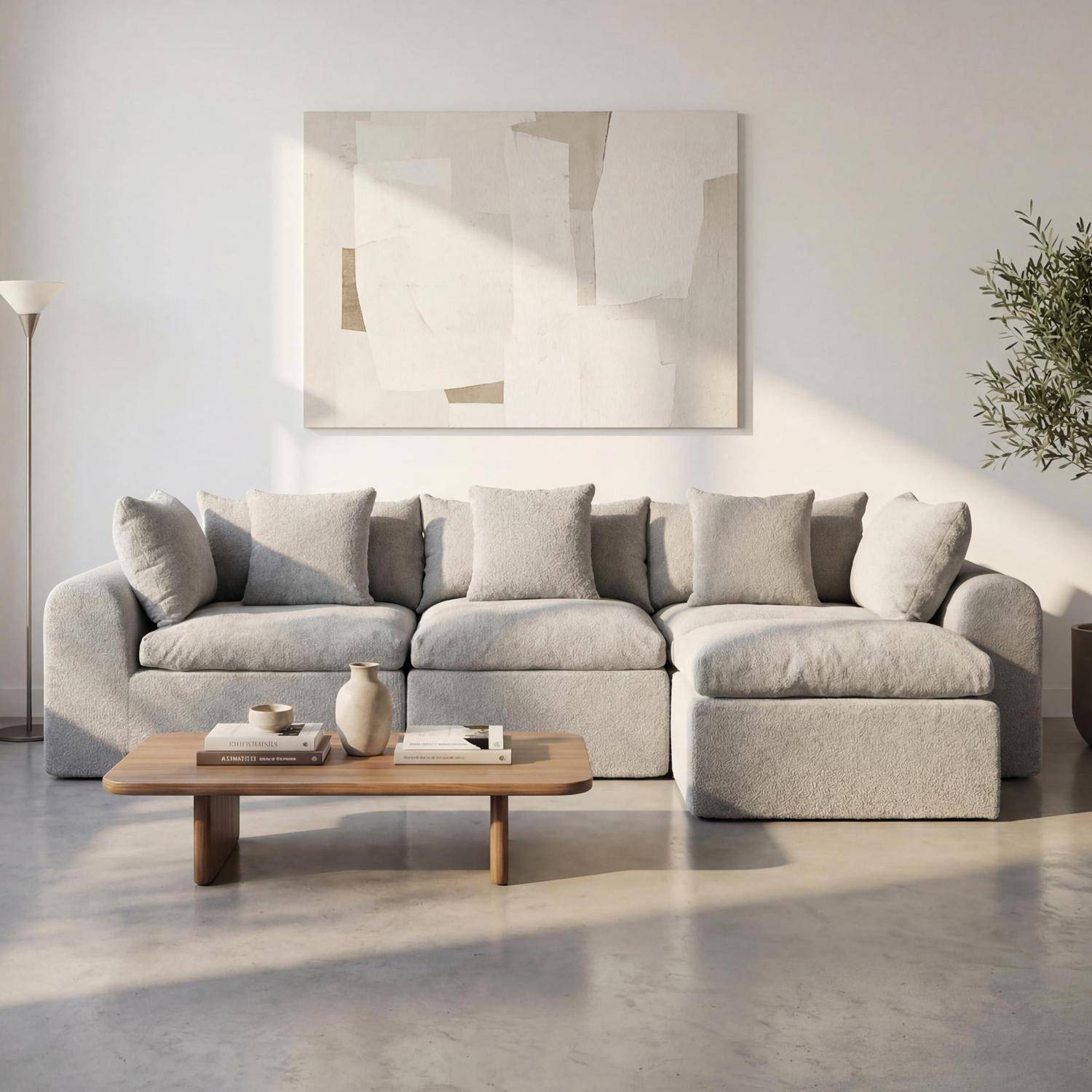 Modernes Wohnzimmer mit einem hellgrauen Ecksofa, Holzcouchtisch, abstrakter Wandkunst und Topfpflanze in weichem Naturlicht.