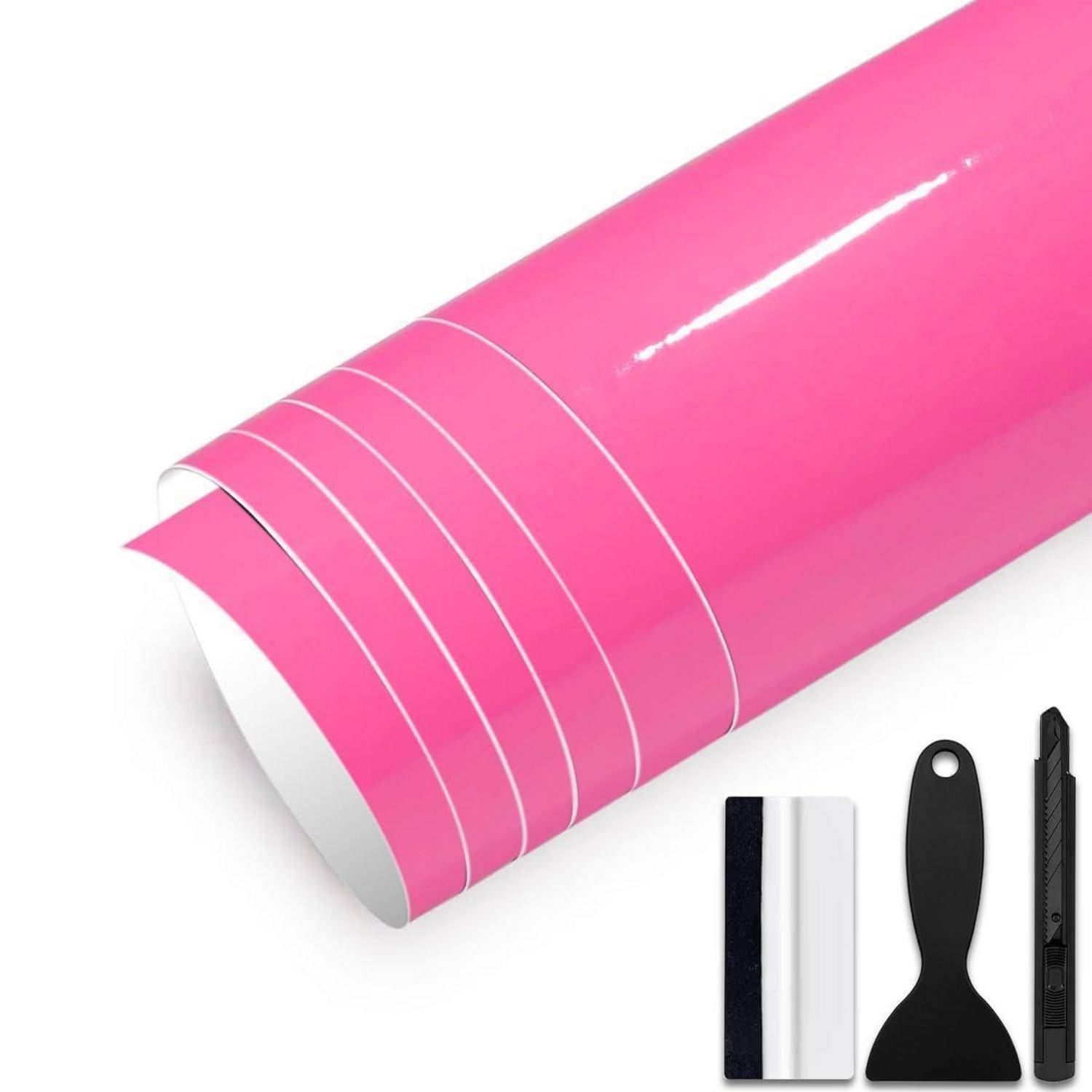 Rosa selbstklebende Vinylrolle mit Applikationsspachtel und Universalmesser auf weißem Hintergrund, mit geschnittener und abziehbarer Kante.