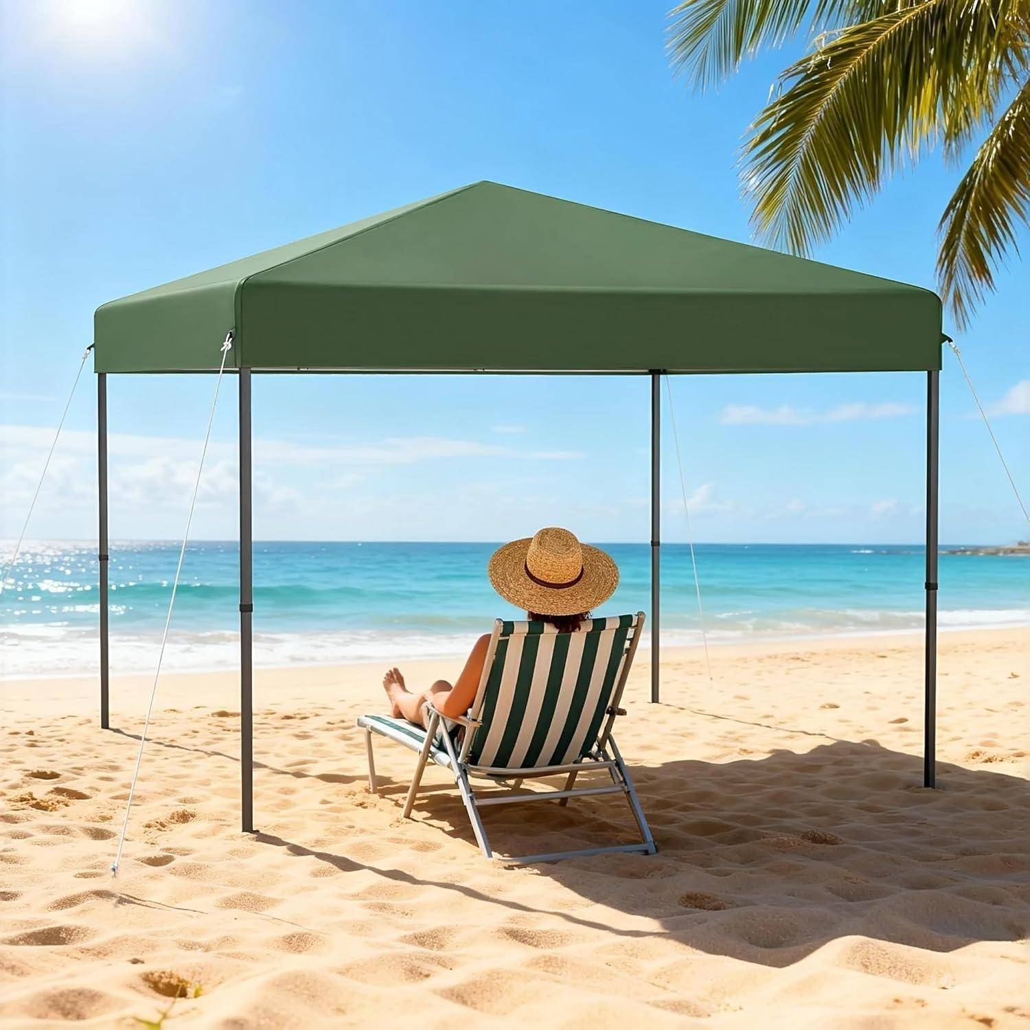 Person, die sich in einem gestreiften Strandsessel unter einem grünen Sonnendach an einem sonnigen Sandstrand entspannt, mit Blick auf den Ozean und Palmenwedeln über dem Kopf.