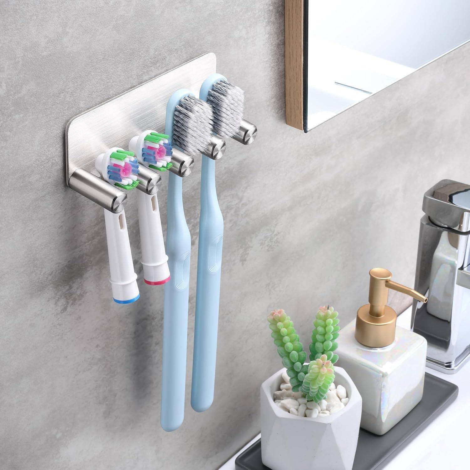 An der Wand montierter Zahnbursthalter mit vier elektrischen Zahnbürsten neben einem Badezimmerspülbecken, Spiegel, Seifenspender und kleinem Topf mit Sukkulente.