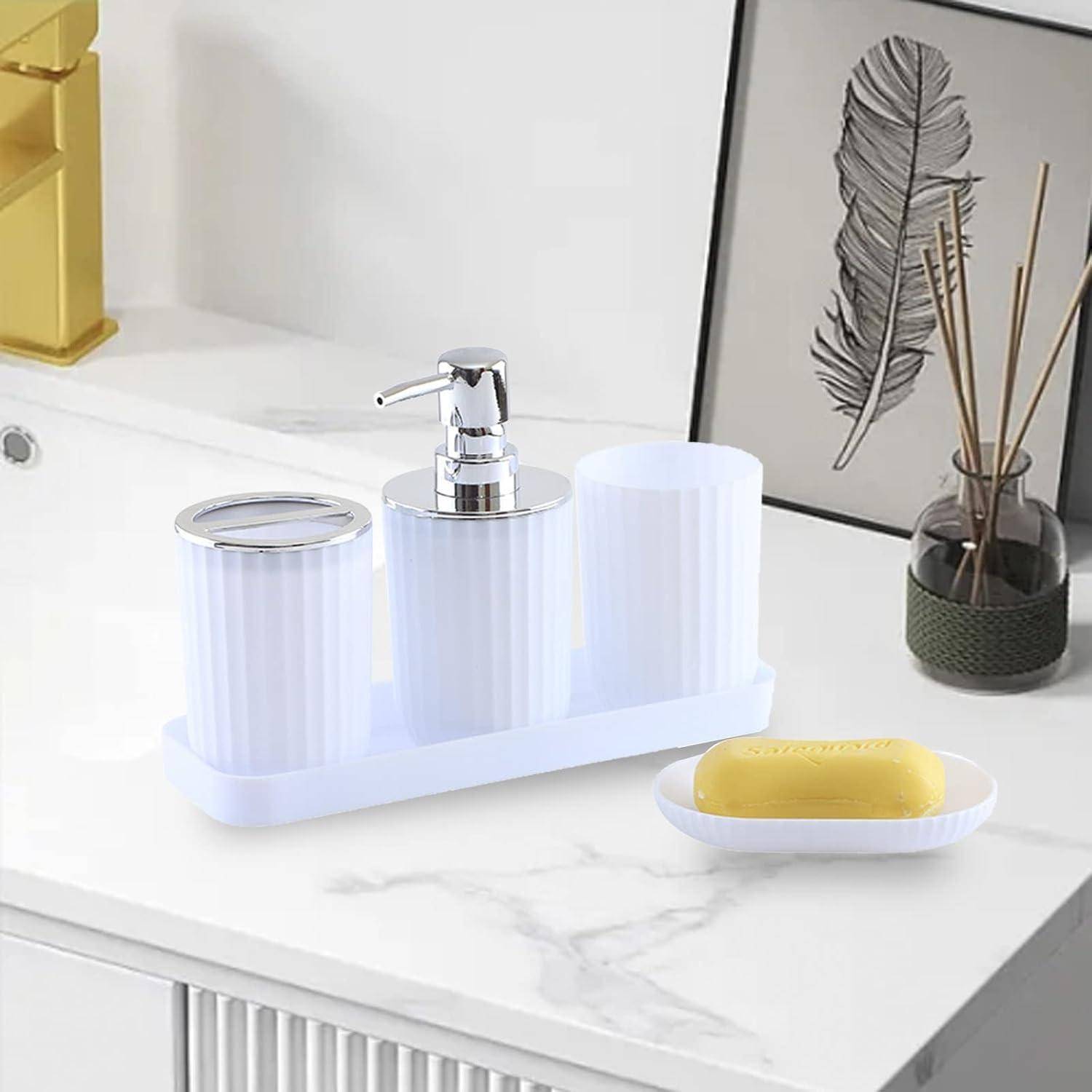 Ein dreiteiliger weißer Badezimmer-Spender-Set auf einer Marmorarbeitsplatte, mit einer Seifenschale, die einen gelben Riegel hält, und einem dekorativen gerahmten Druck sowie einem Raumdüfter mit Bambusstäbchen im Hintergrund.