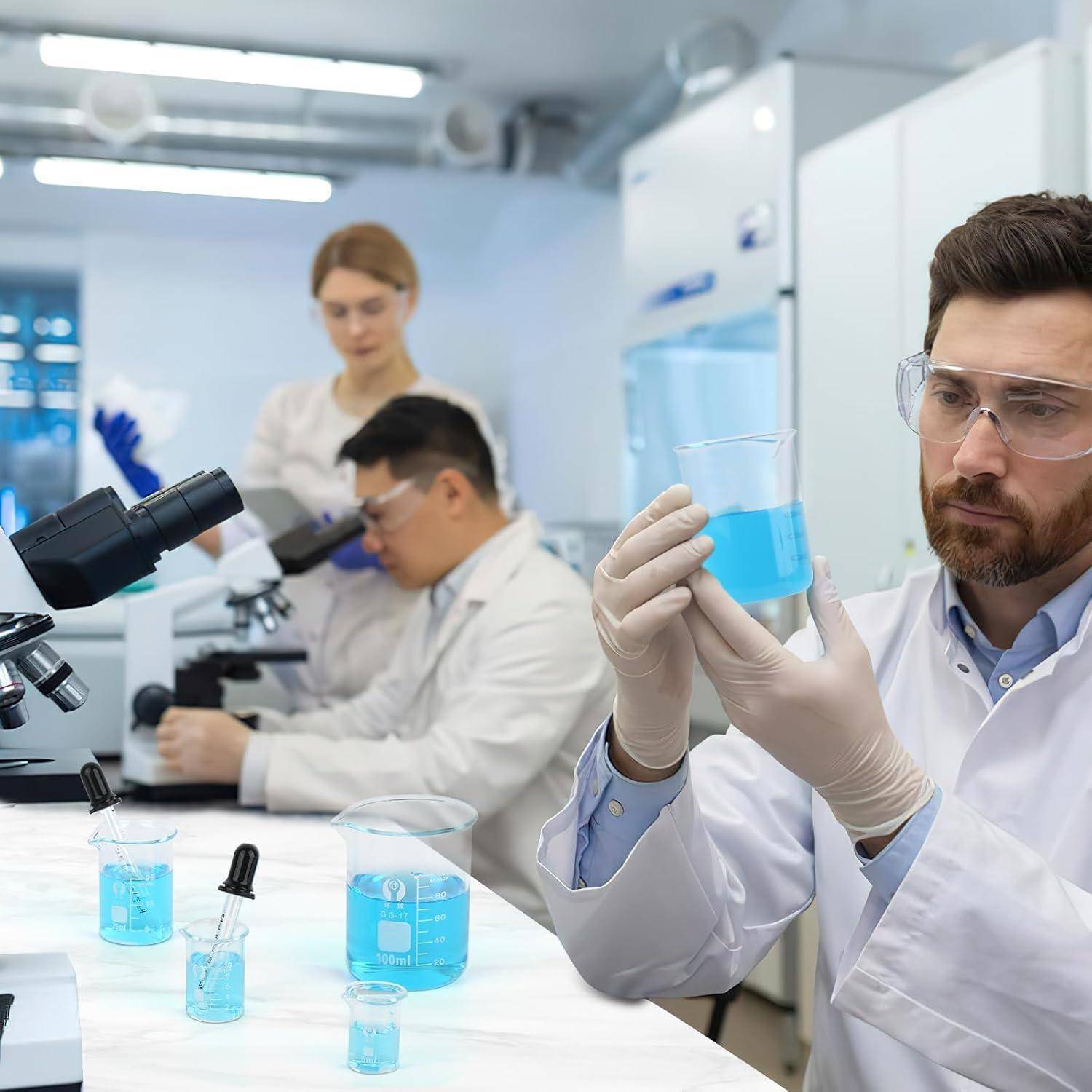 Wissenschaftler in einem Labor untersuchen blaue Flüssigkeitsproben mit Mikroskopen und Glaswaren.