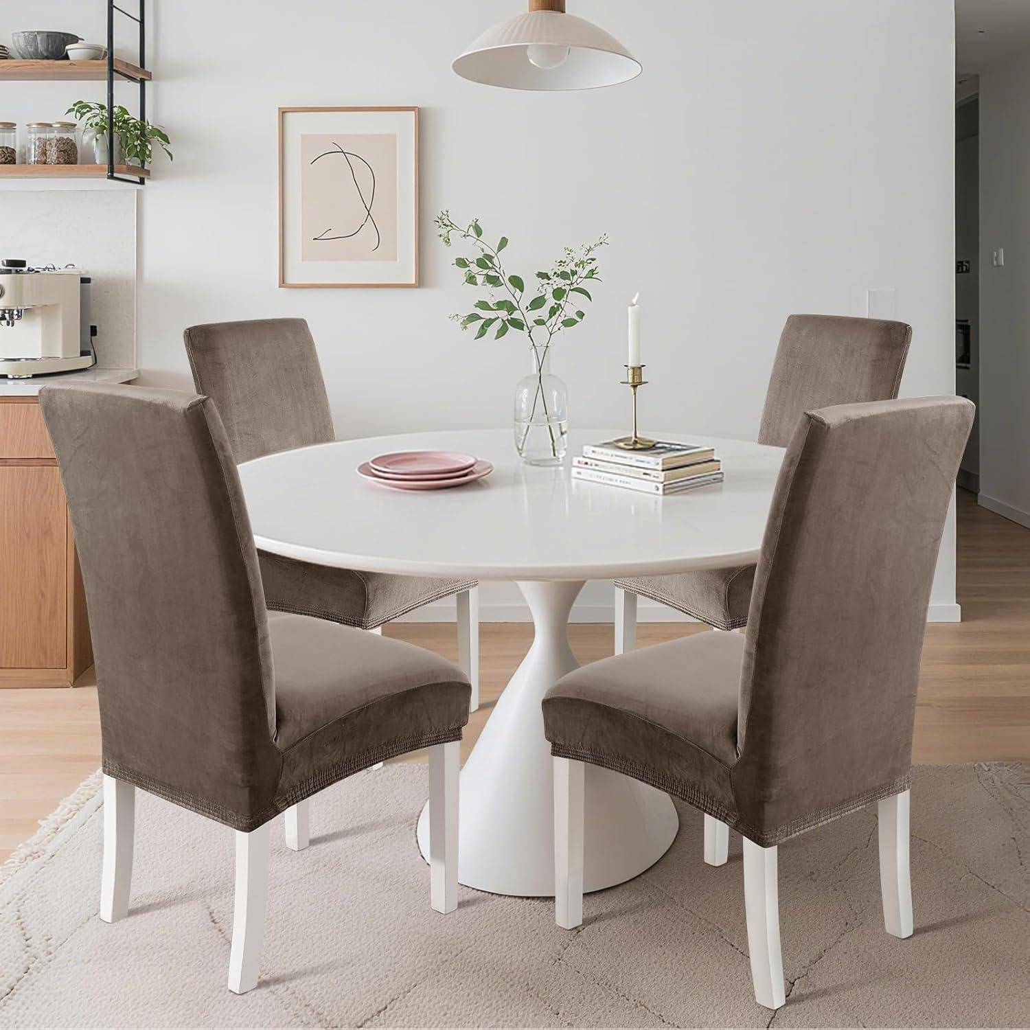 Moderner Essbereich mit einem runden weißen Tisch, vier taupefarbenen gepolsterten Stühlen und einfacher Dekoration in einem hellen, minimalistischen Zimmer.
