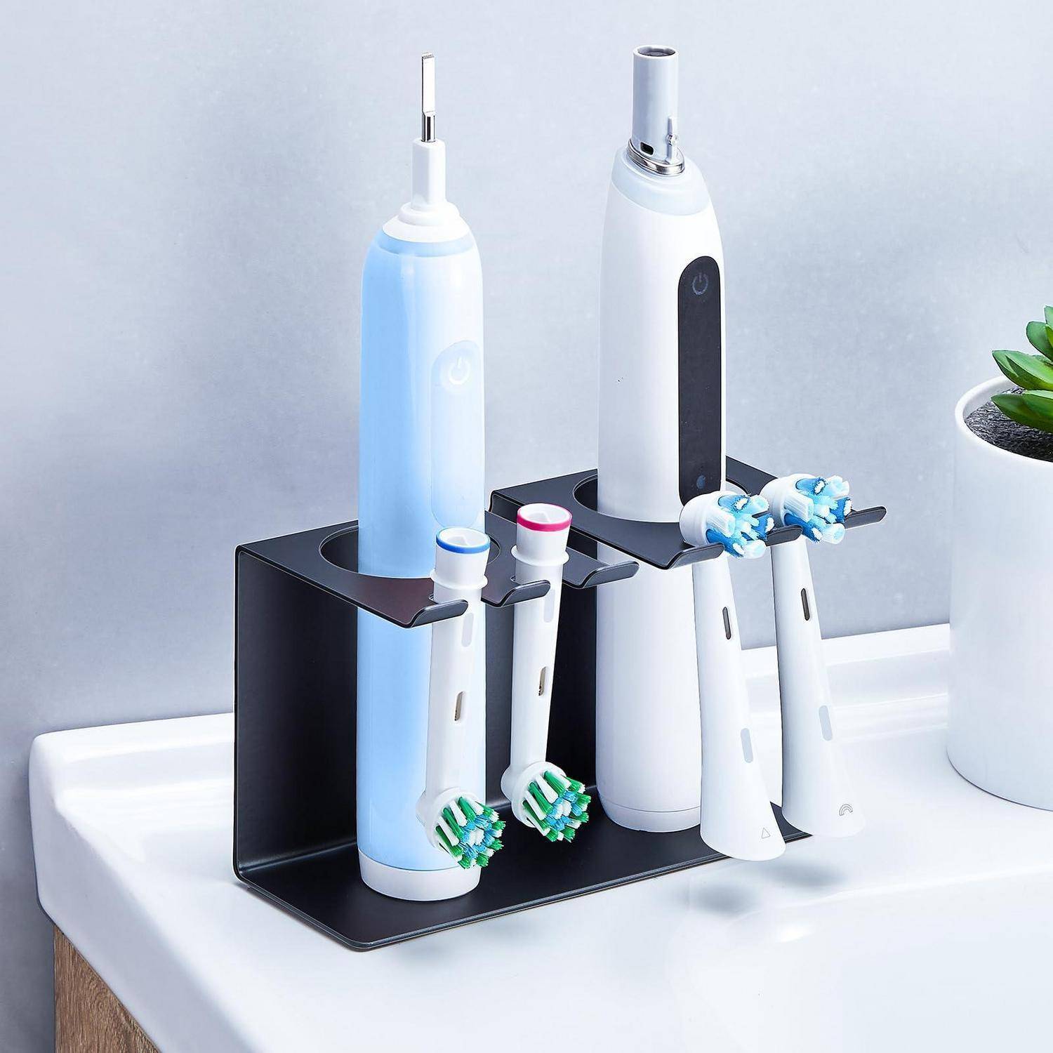 Elektrischer Zahnbürstenhalter-Organizer mit zwei Zahnbürsten, zwei elektrischen Zahnbürstengriffen und einer blauen Zahnbürste, die auf einem Badezimmerschrank steht.