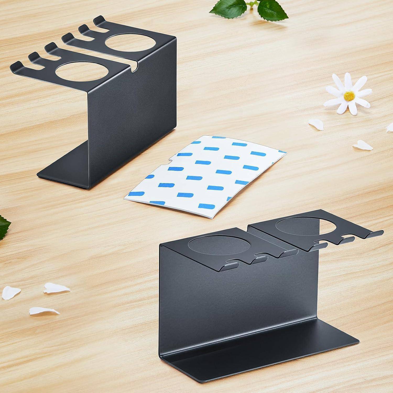 Zwei schwarze Metallständerhalter mit kreisförmigen Ausschnitten zeigen eine blau-weiß gemusterte Karte zwischen sich auf einer hellen Holzoberfläche mit kleinen Blumen und Blütenblättern.