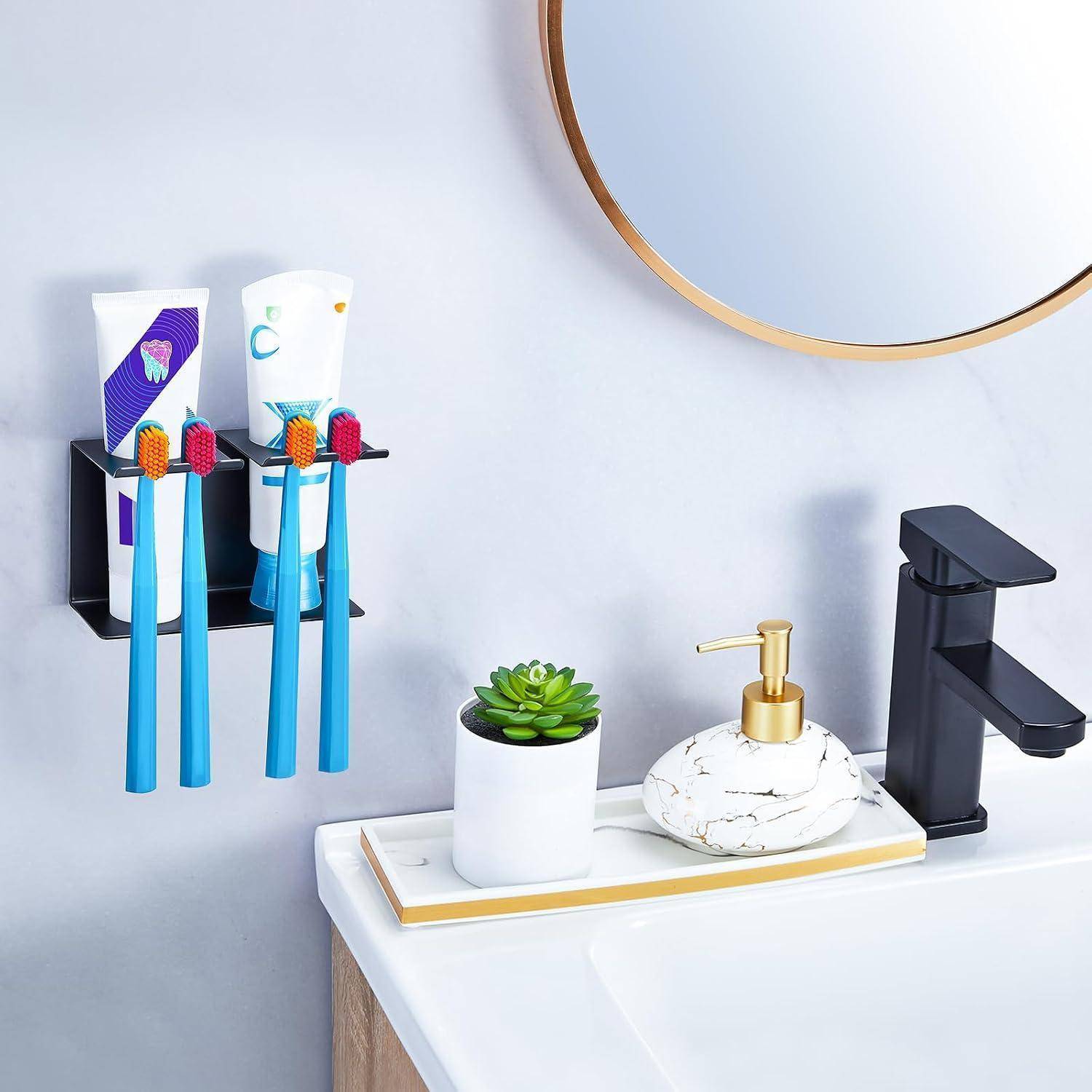 Modernes Badezimmer-Waschbecken mit an der Wand montiertem Zahnbürstenhalter, Zahnpasta, Sukkulente, Seifenspender und schwarzem Wasserhahn neben einem runden Spiegel.