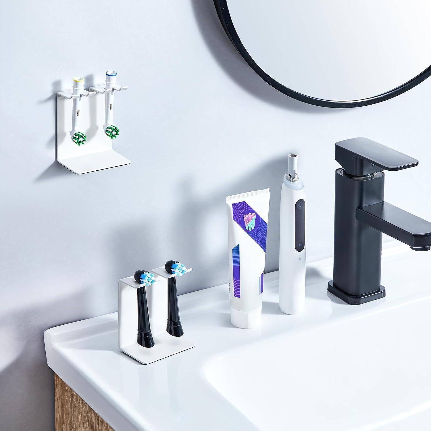 Badezimmerablage mit elektrischen Zahnbürsten, Zahnpasta und Seifenspendern, die neben einem schwarzen Wasserhahn und Waschbecken angeordnet sind.