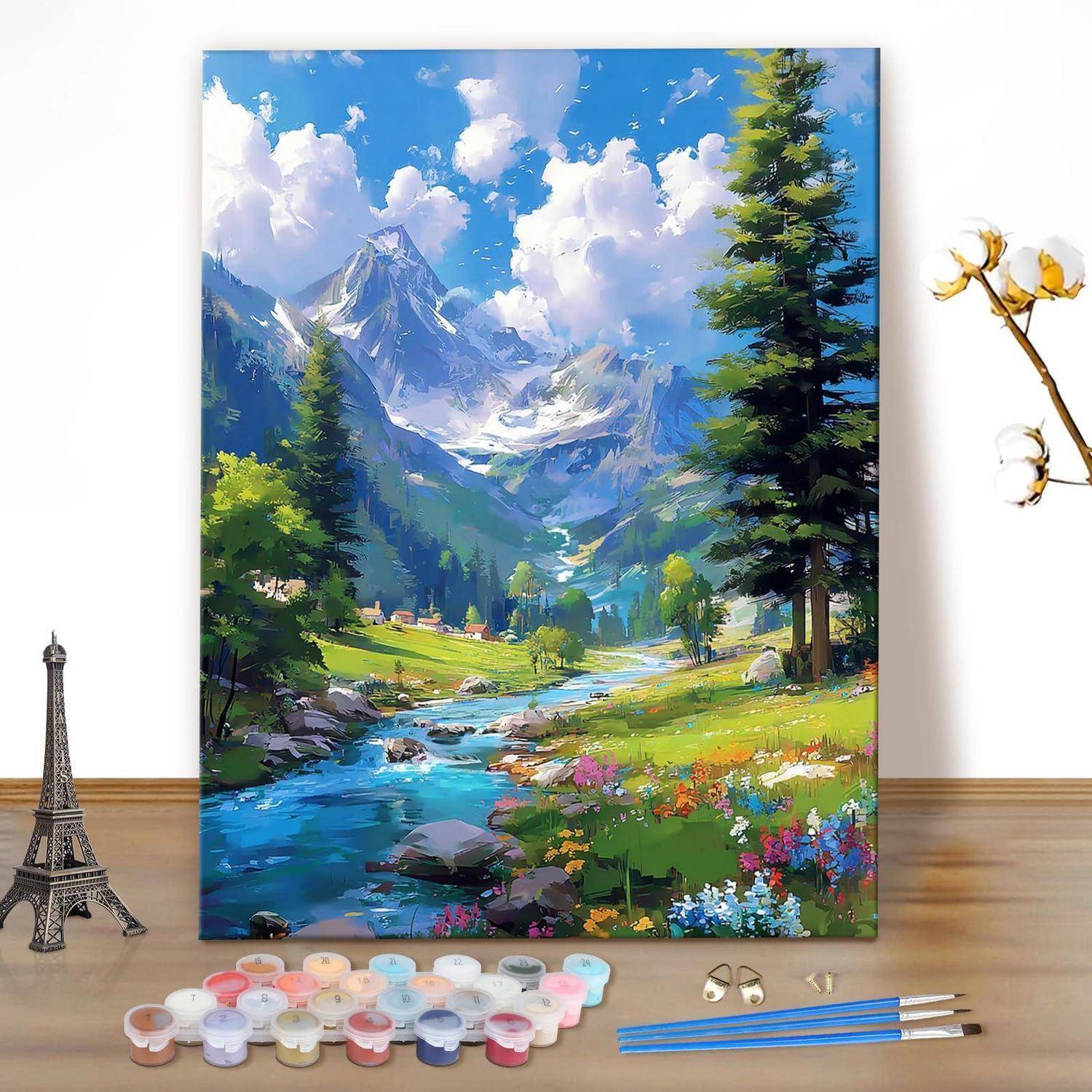 Gemalte Berglandschaft auf Leinwand mit Flusstal, Kiefern, Wildblumen und schneebedeckten Gipfeln, dargestellt mit Kunstbedarf in der Nähe.