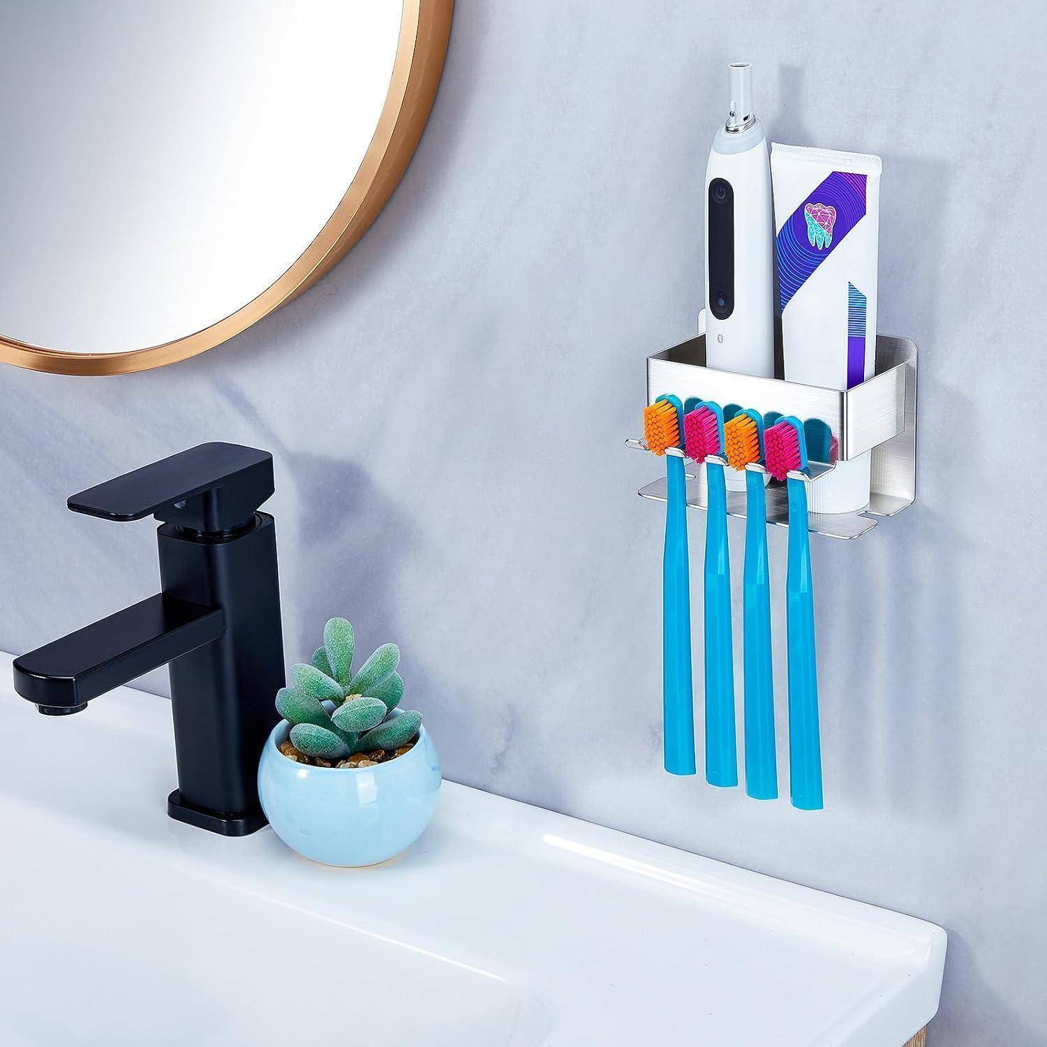 Badezimmerwaschtisch mit schwarzem Wasserhahn, kleine Pflanze und an der Wand montierter Organizer mit elektrischer Zahnbürste, Zahnpasta und vier Zahnbürsten.