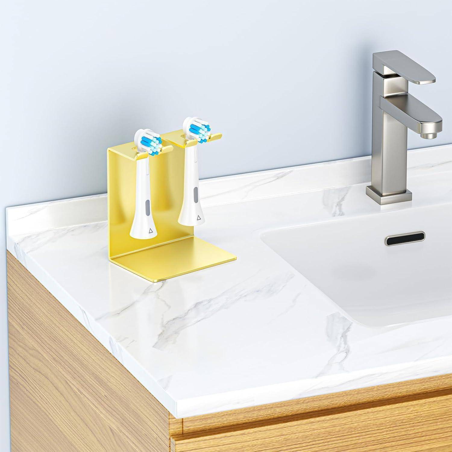 Gelber an der Wand montierter Zahnbürstenhalter mit zwei elektrischen Zahnbürsten neben einem Badezimmerspülbecken und Wasserhahn auf einer Marmor-Arbeitsplatte.