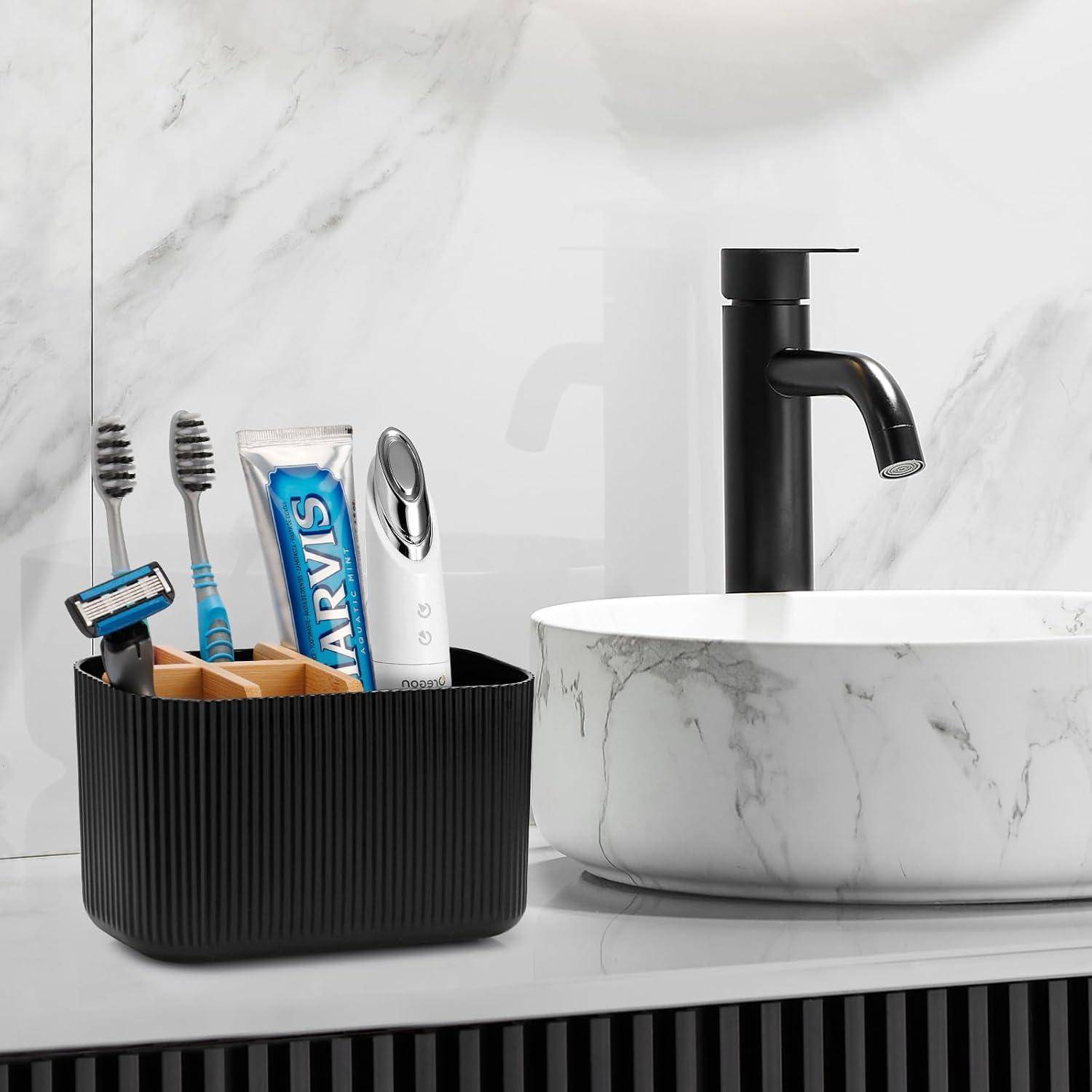 Modernes Badezimmerbecken mit schwarzem Wasserhahn, Marmorwaschbecken und Organizer mit Zahnbürsten, Rasierer und Zahnpasta.