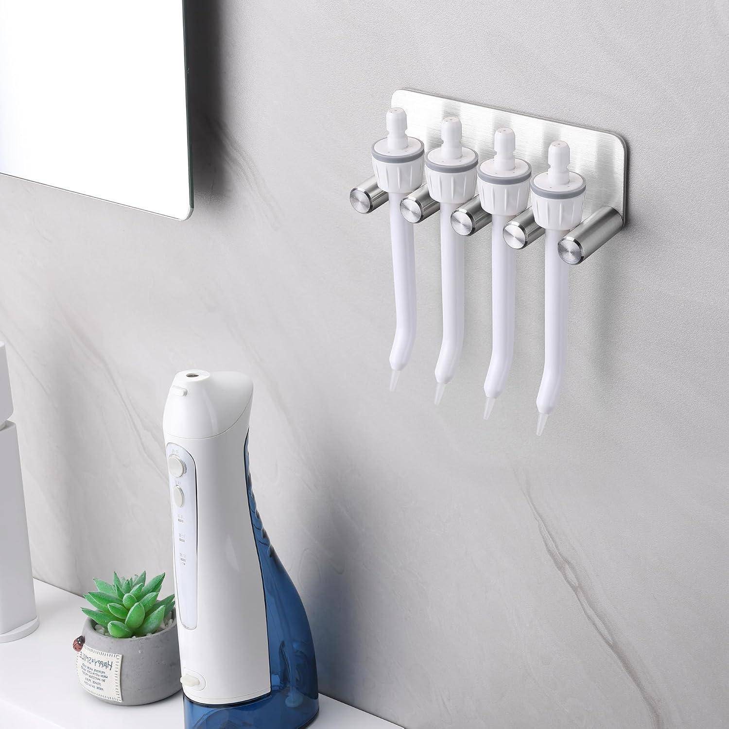 Wandmontierter Zahnbürstensterilisator/Halter für das Badezimmer mit vier Zahnbürsten über einer Arbeitsfläche, neben einem Spiegel und einer elektrischen Zahnbürsten-Basis.