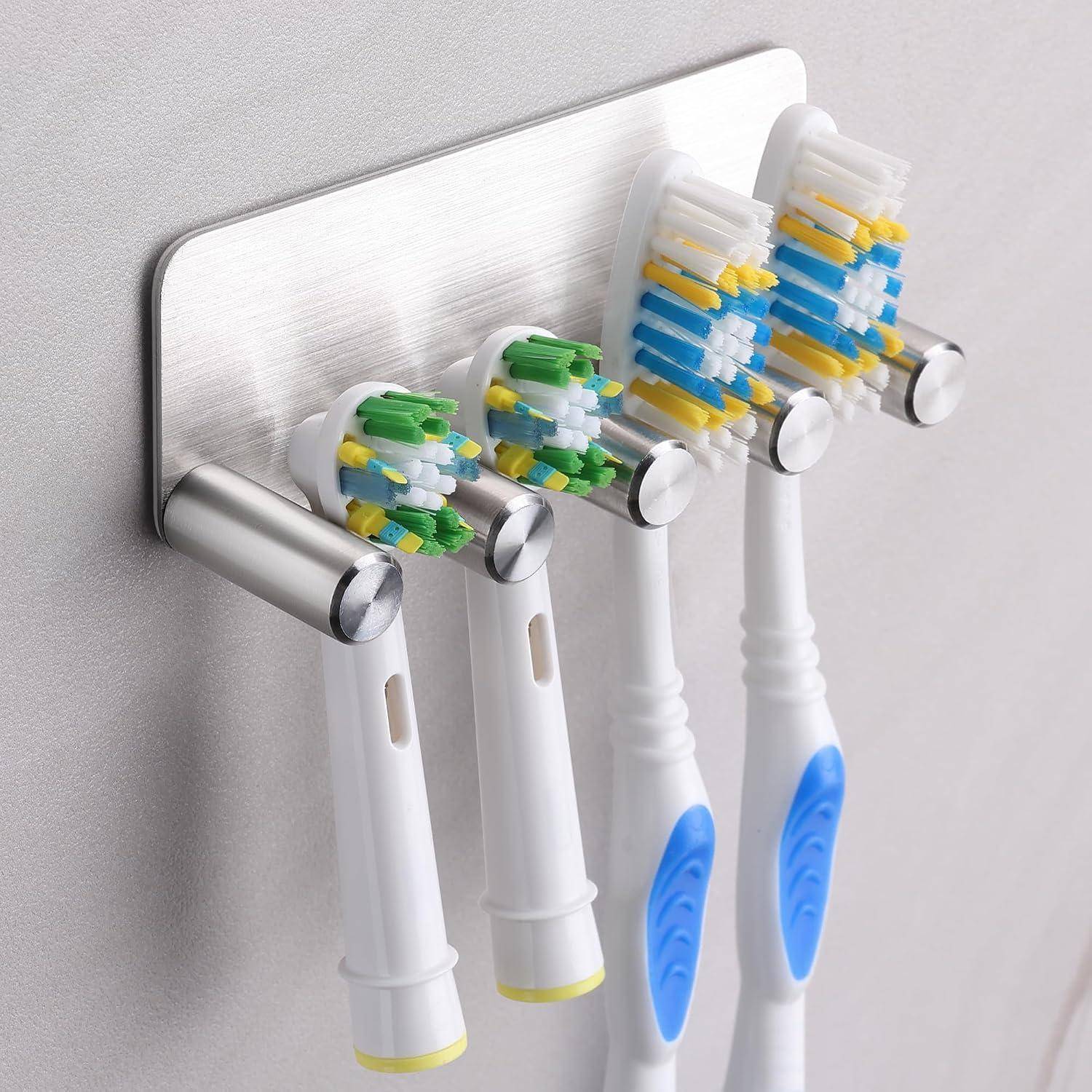 An der Wand befestigter Zahnbürstenhalter mit vier Elektrozahnbürsten, die kopfüber an Metallstiften hängen.