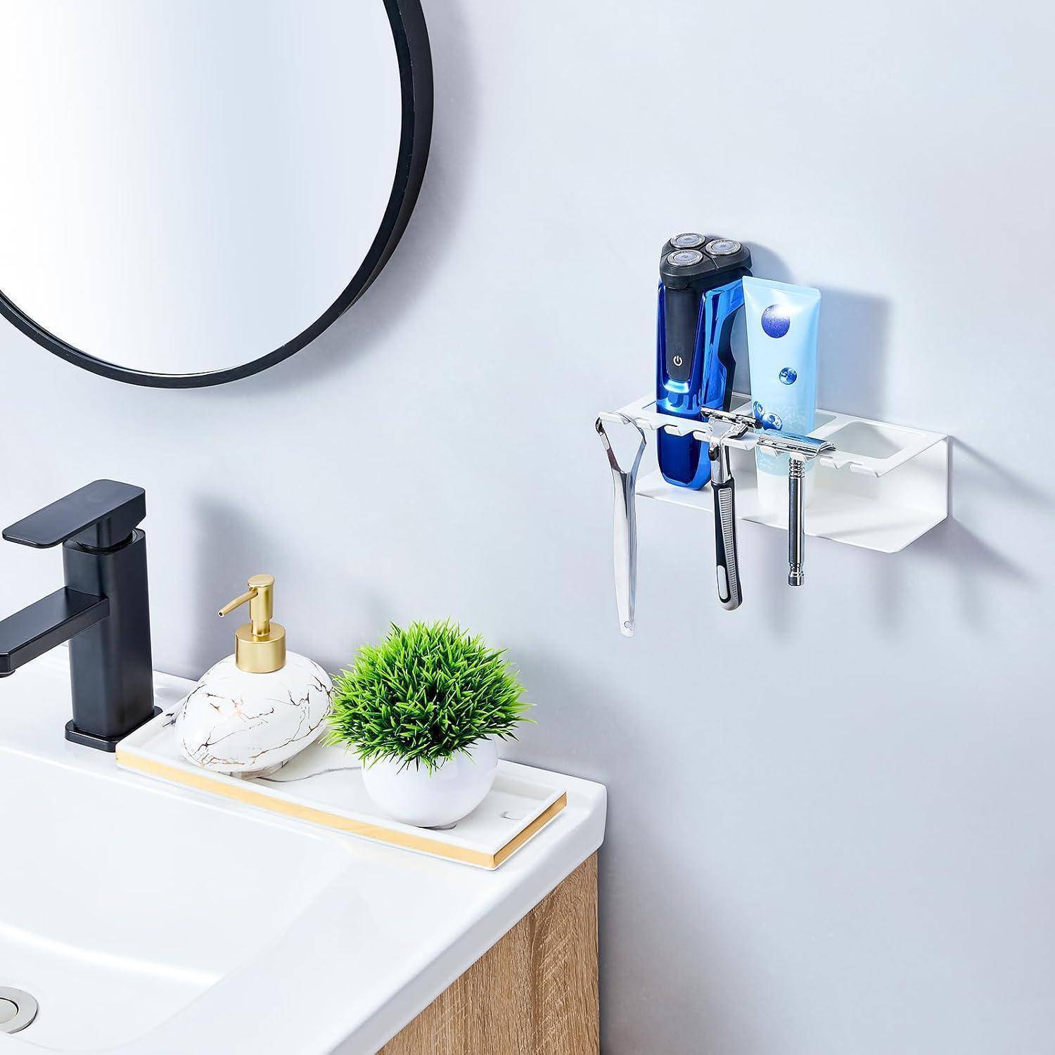 Badezimmerbecken mit schwarzem Wasserhahn, Seifenspender, Pflanze und an der Wand montiertem Halter, in dem eine elektrische Zahnbürste und ein Rasierer neben einem Spiegel gelagert werden.