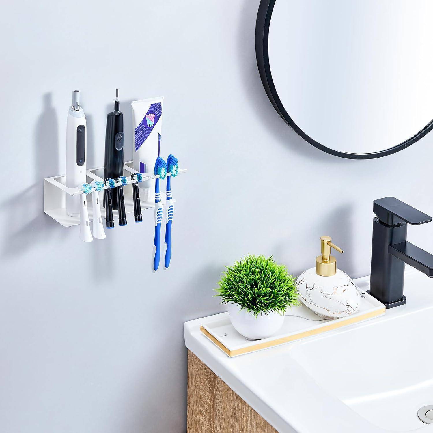 Badezimmerspüle mit einem wandmontierten Zahnbursthalter, der Elektrozahnbürsten und eine Tube hält, neben einem Spiegel, einem Wasserhahn, einem Seifenspender und einer kleinen Pflanze.