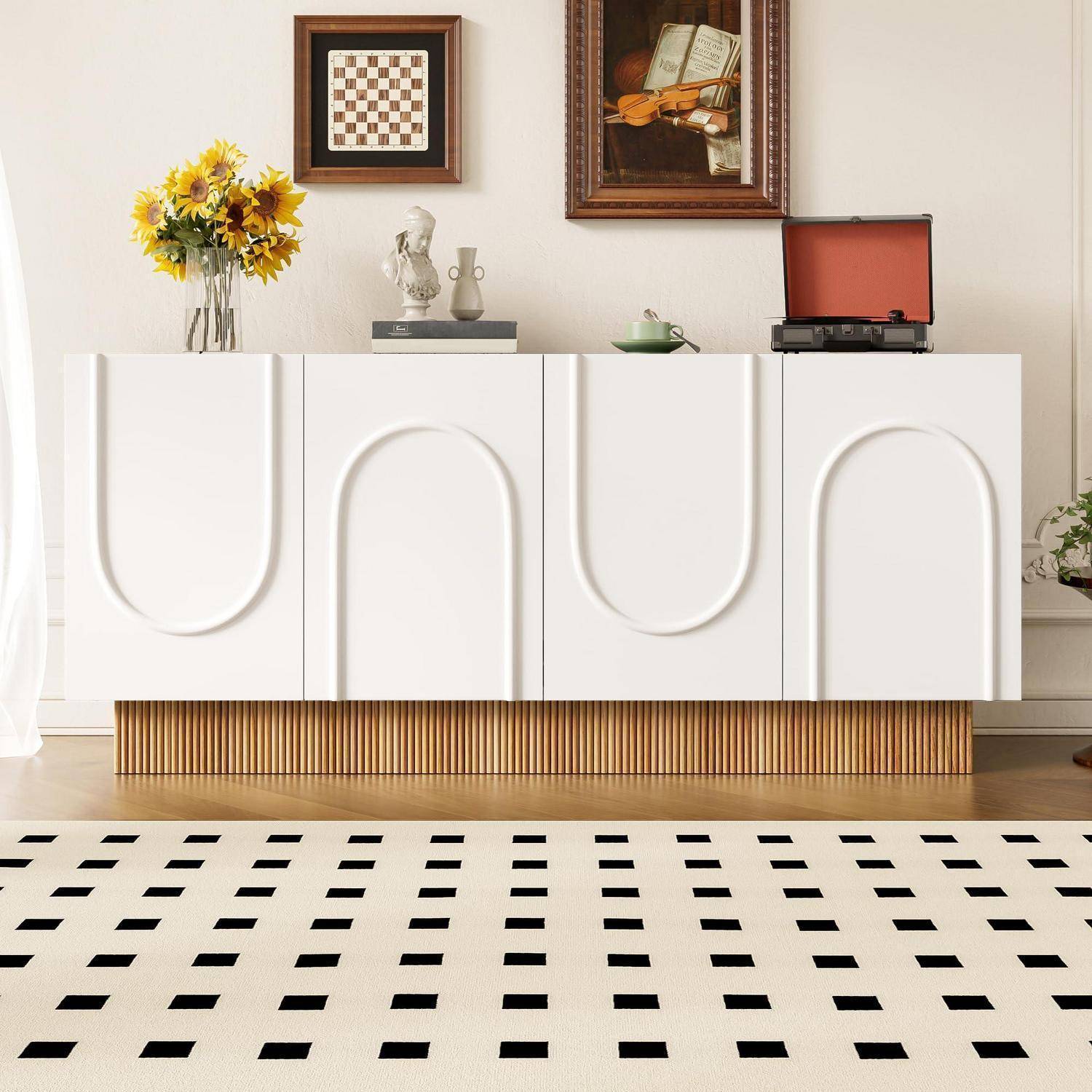 Weißes Sideboard mit dekorativen Regalen, Blumen, Kunstwerken und einem Plattenspieler über einem schwarz-weißen gemusterten Teppich in einem hellen Raum.
