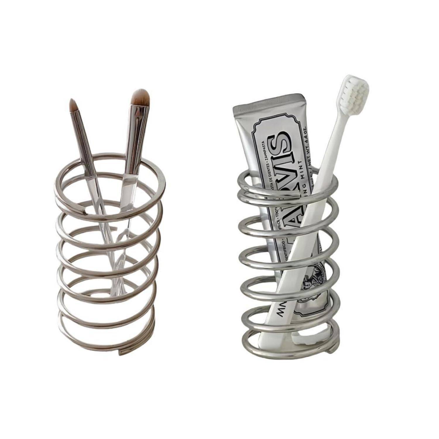 Zwei Metallspiralhalter auf weißem Hintergrund: einer hält Makeup-Pinsel, der andere hält eine Zahnpastatube und eine Zahnbürste.